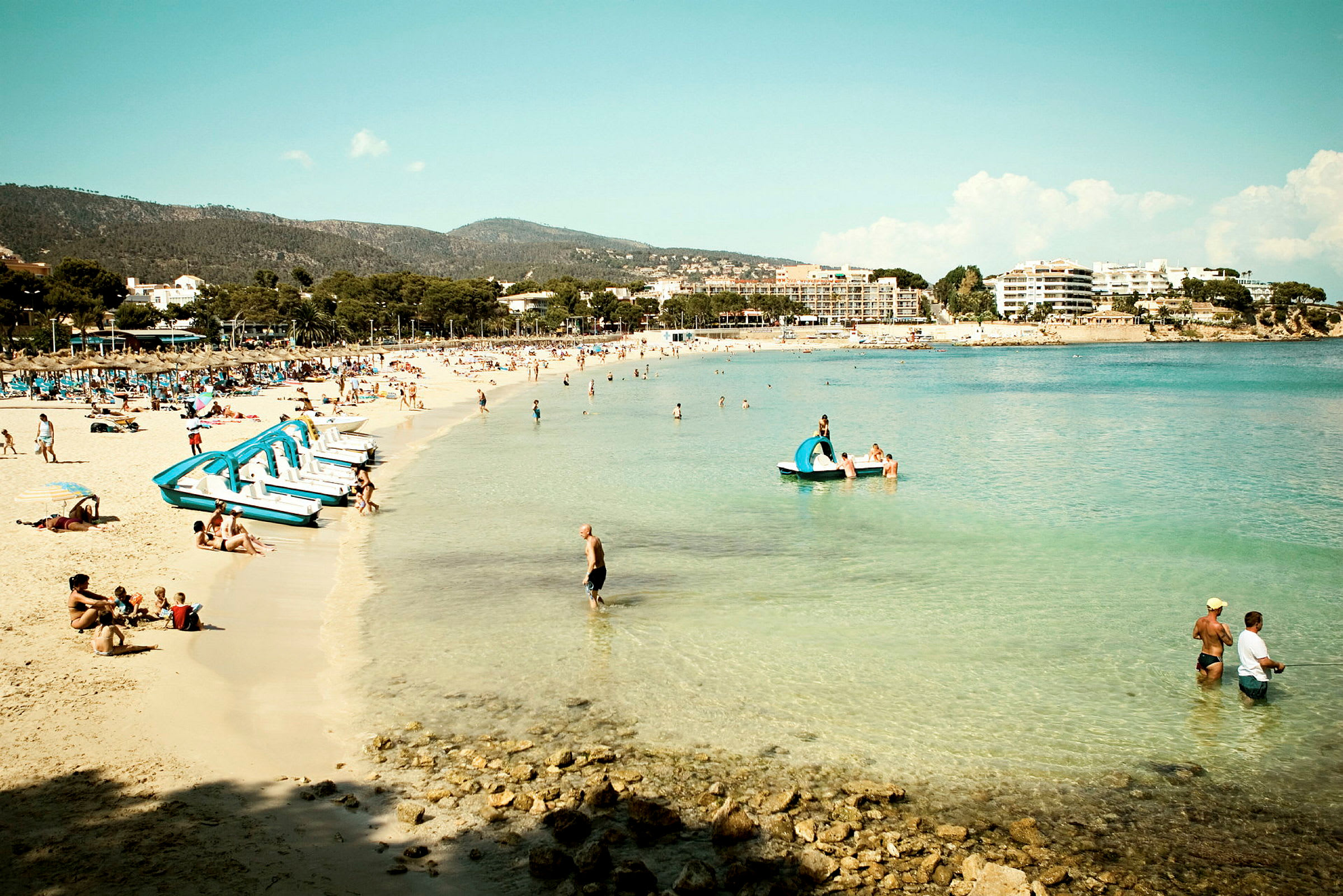 Strand med turkis vand og feriegæster. (AI-genereret tekst)