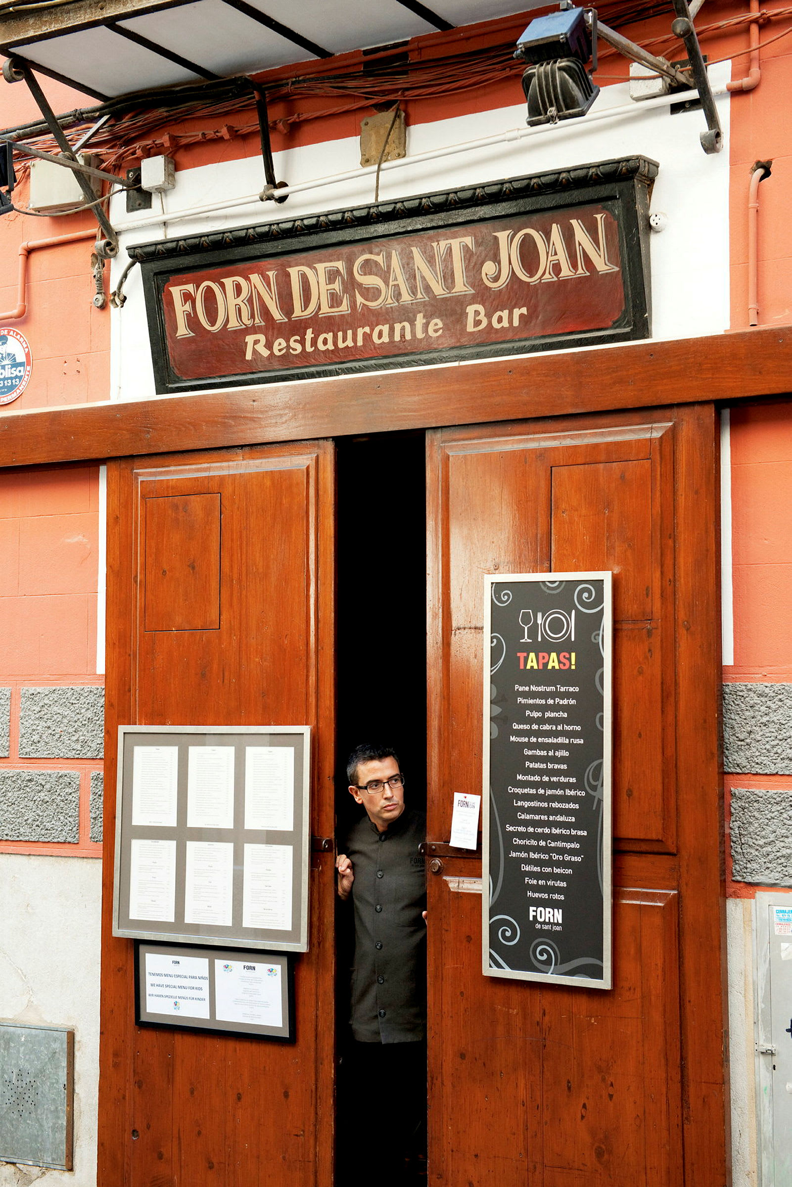 Indgang til en restaurant og bar med et skilt, der viser navnet 'Forn Desant Joan' og menuer udenfor. (AI-genereret tekst)