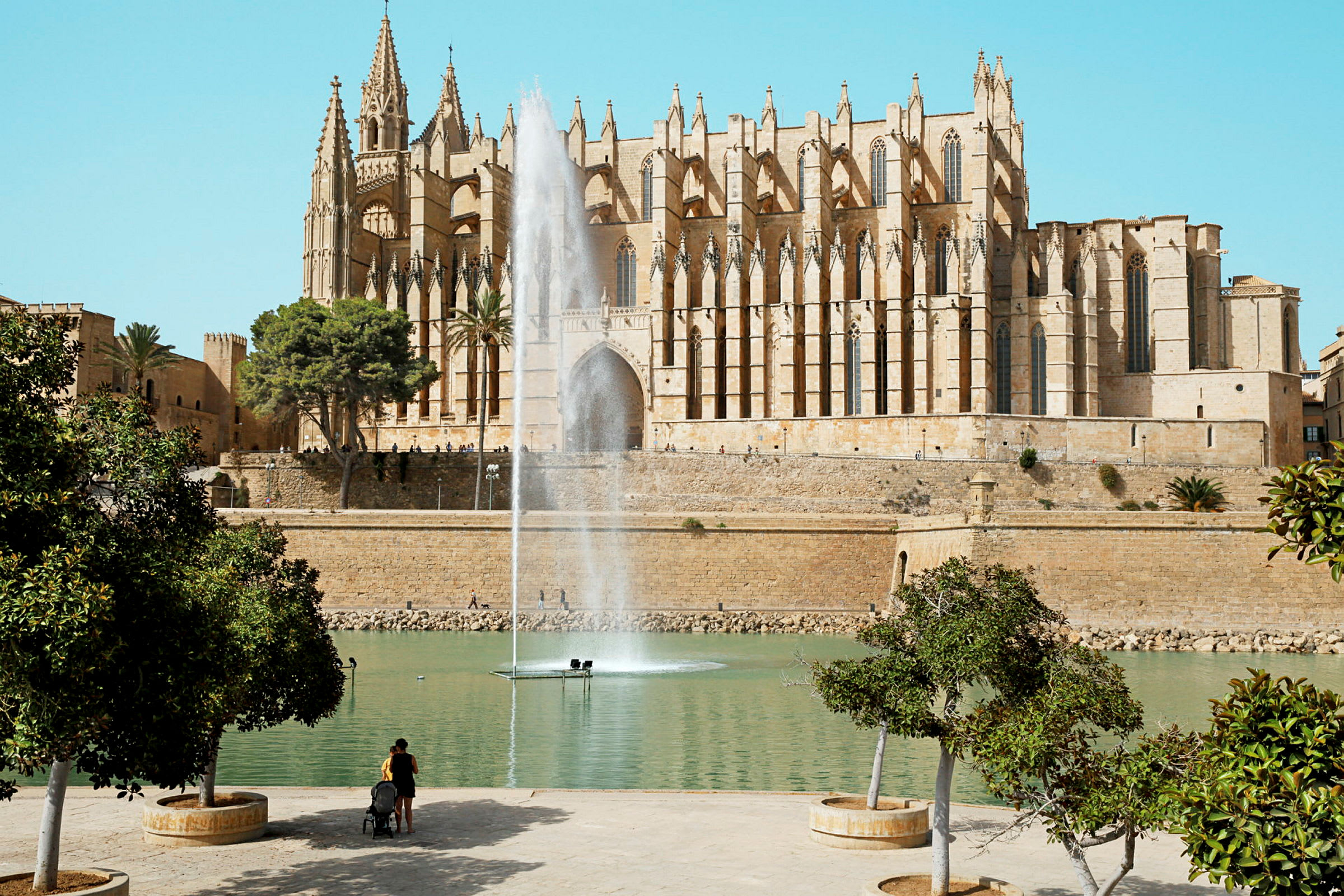 Gotisk katedral i Palma de Mallorca med springvand og grønt område i forgrunden. (AI-genereret tekst)