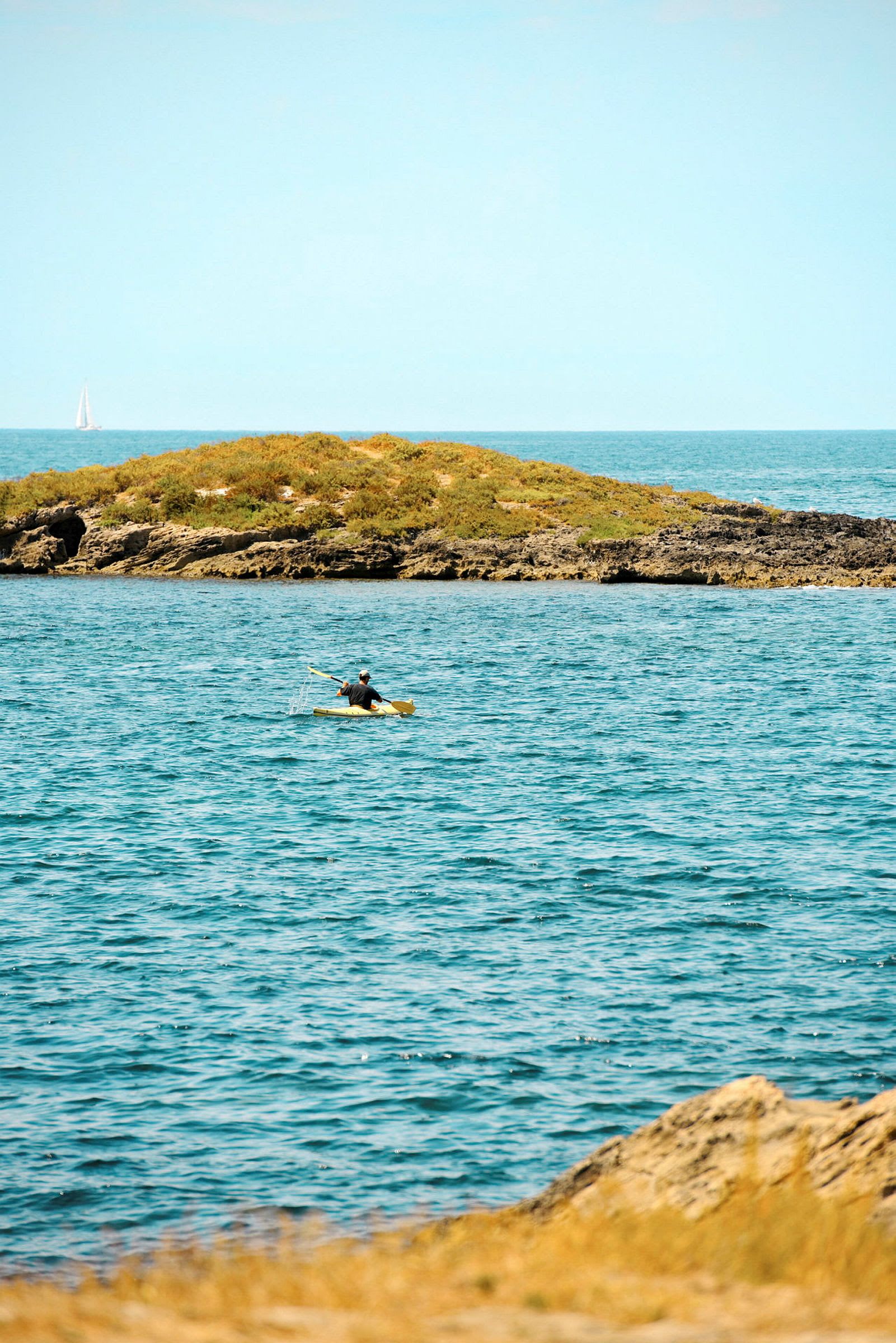 En person ror i kajak på havet nær en lille grøn ø. (AI-genereret tekst)
