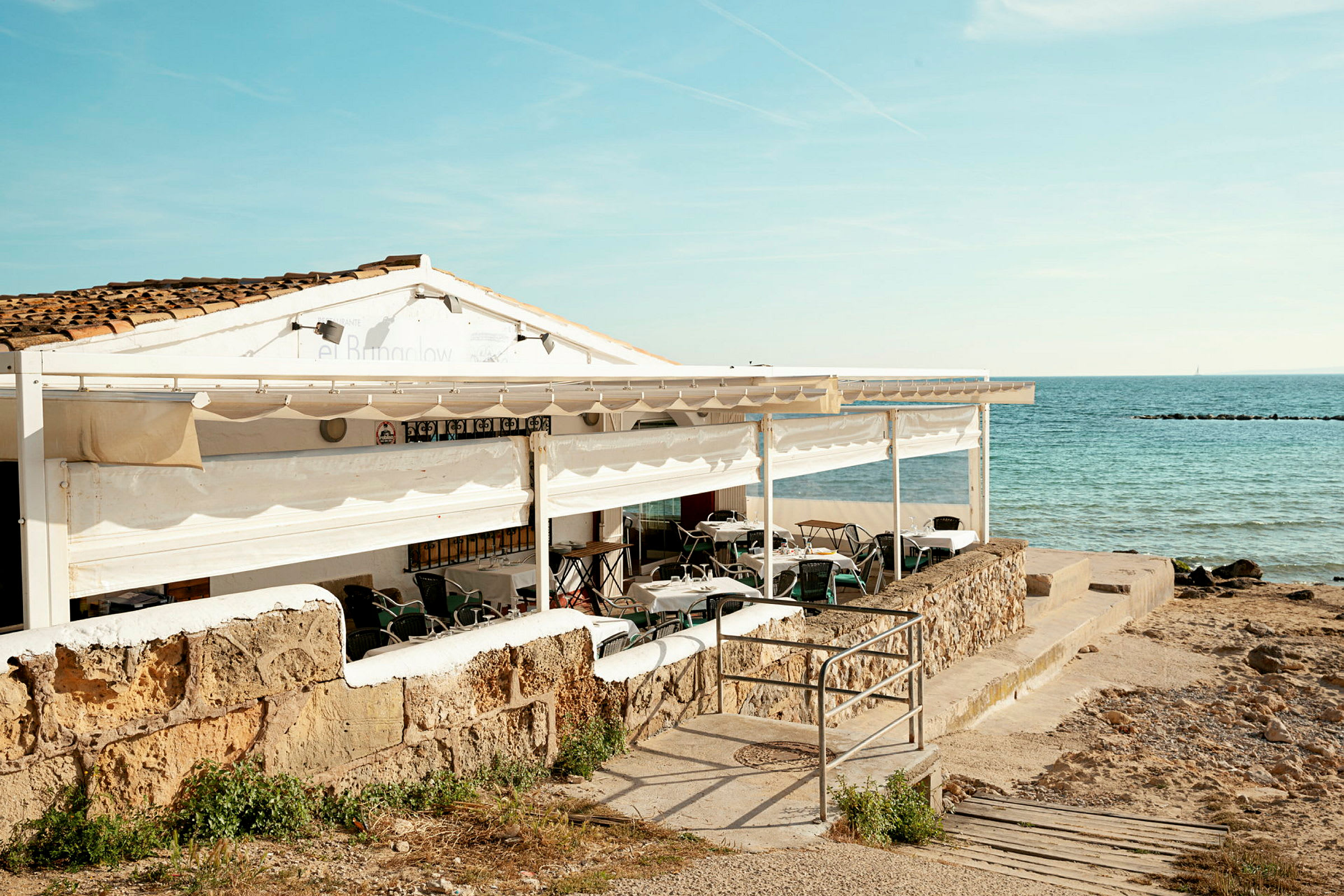 En restaurant med udendørs servering ved havet. (AI-genereret tekst)