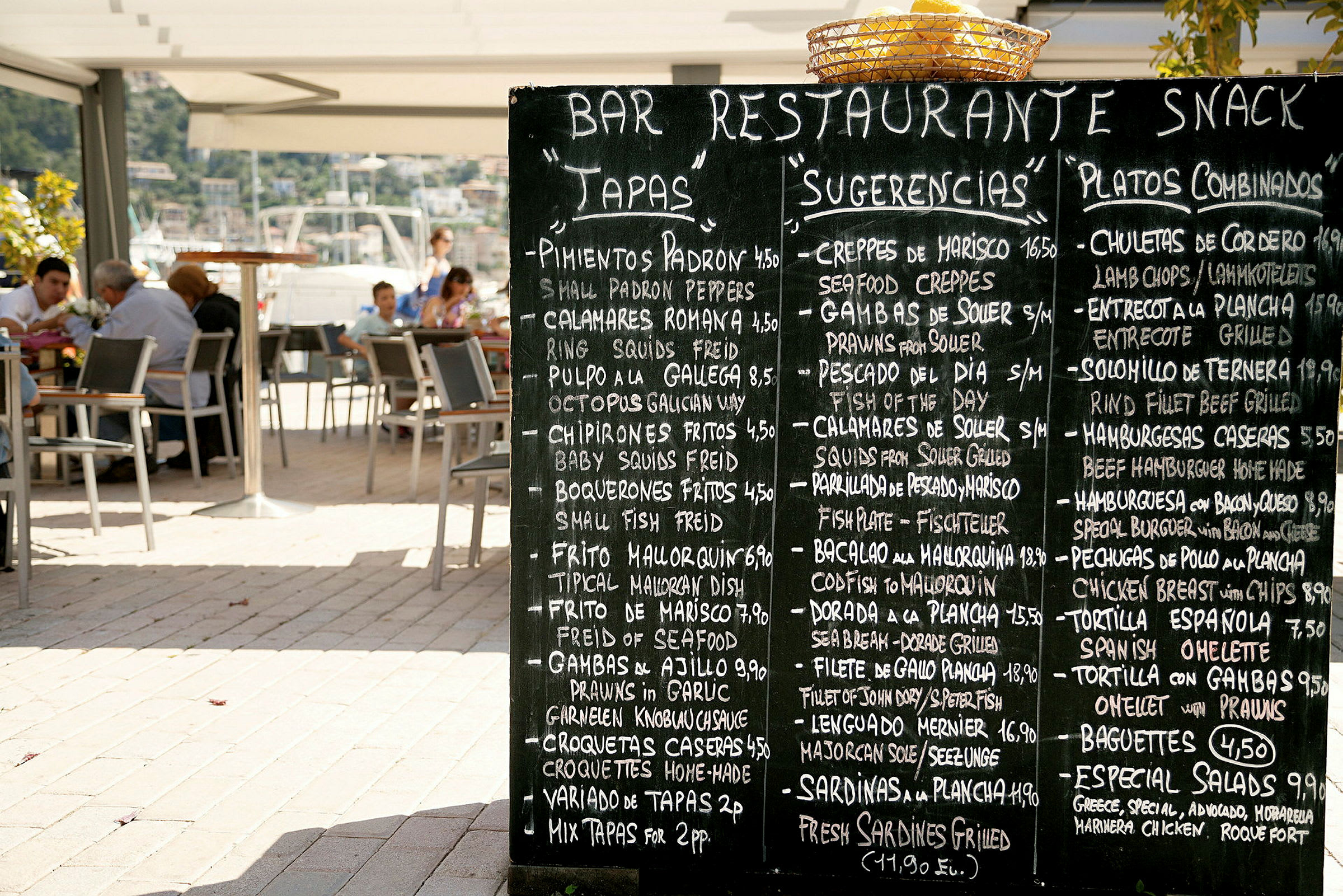 Sort tavle med en menu på en restaurantterrasse. (AI-genereret tekst)