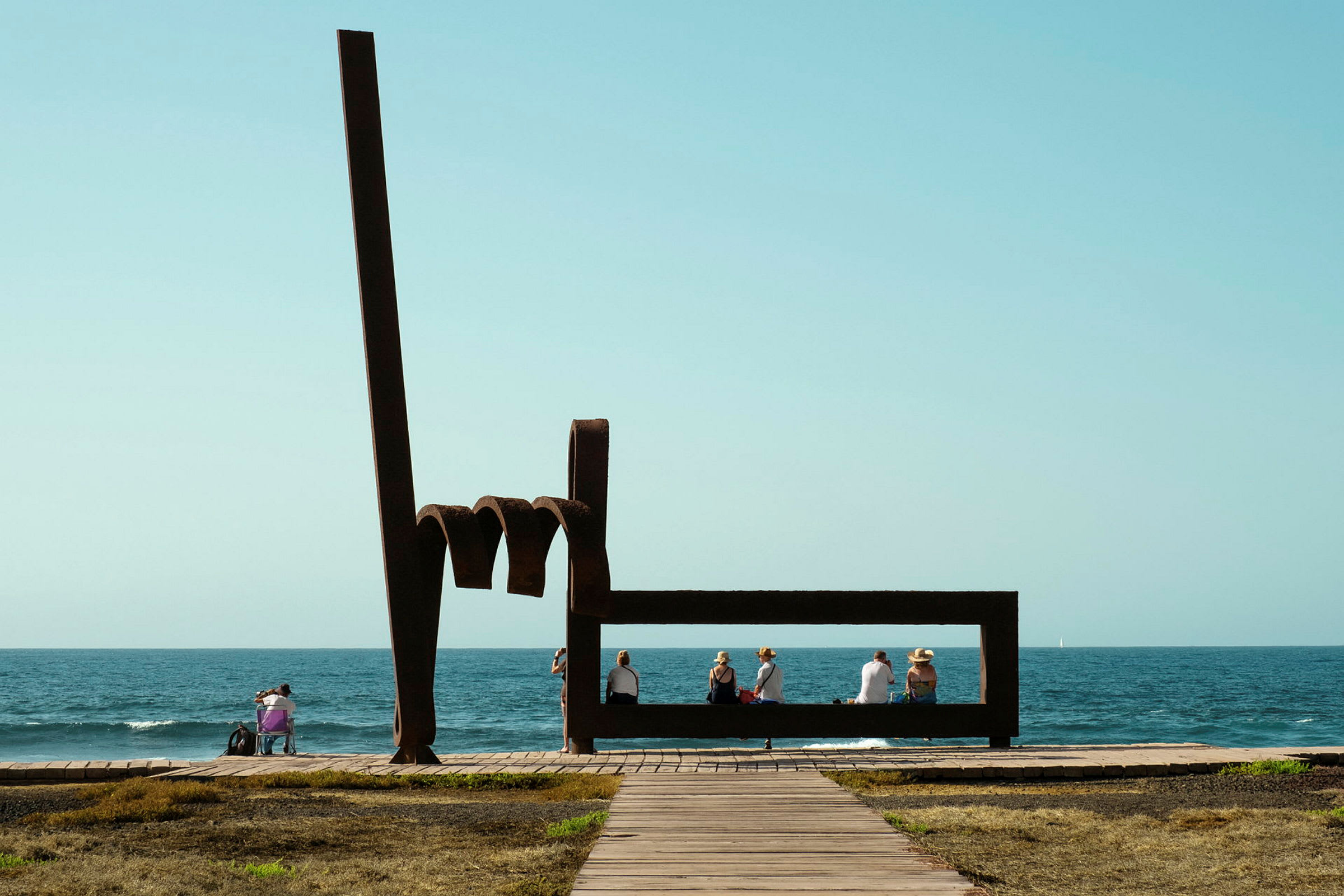Skulptur med mennesker, der sidder ved havet. (AI-genereret tekst)