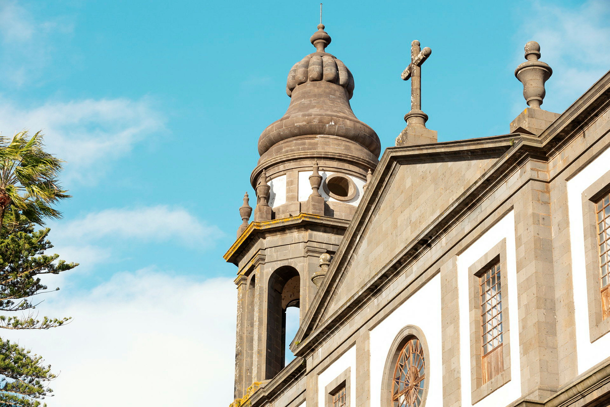 Nærbillede af en kirke med detaljer på kuppel og kors mod klar blå himmel. (AI-genereret tekst)