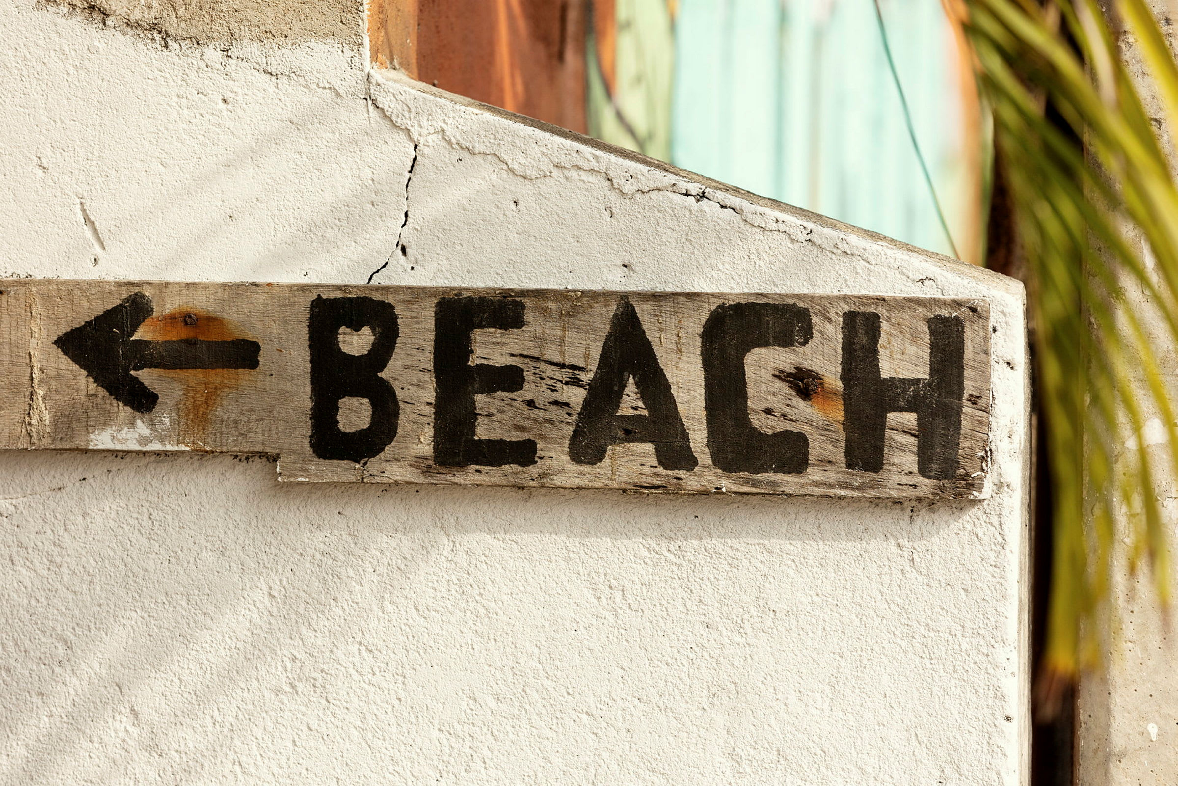 Et træskilt med teksten "BEACH" og en pil peger til venstre. (AI-genereret tekst)