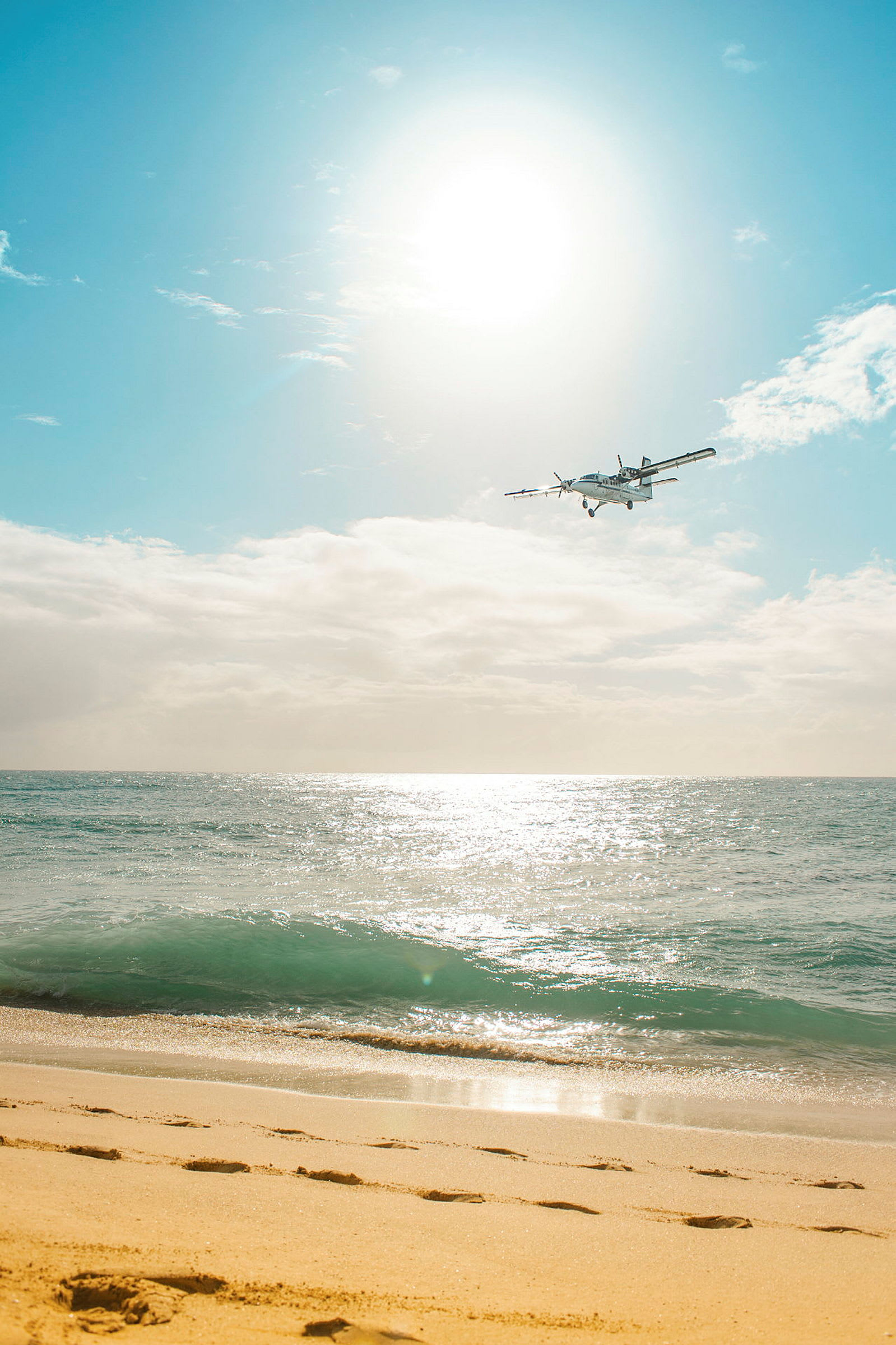 Et fly flyver over en strand og hav under en lys himmel. (AI-genereret tekst)