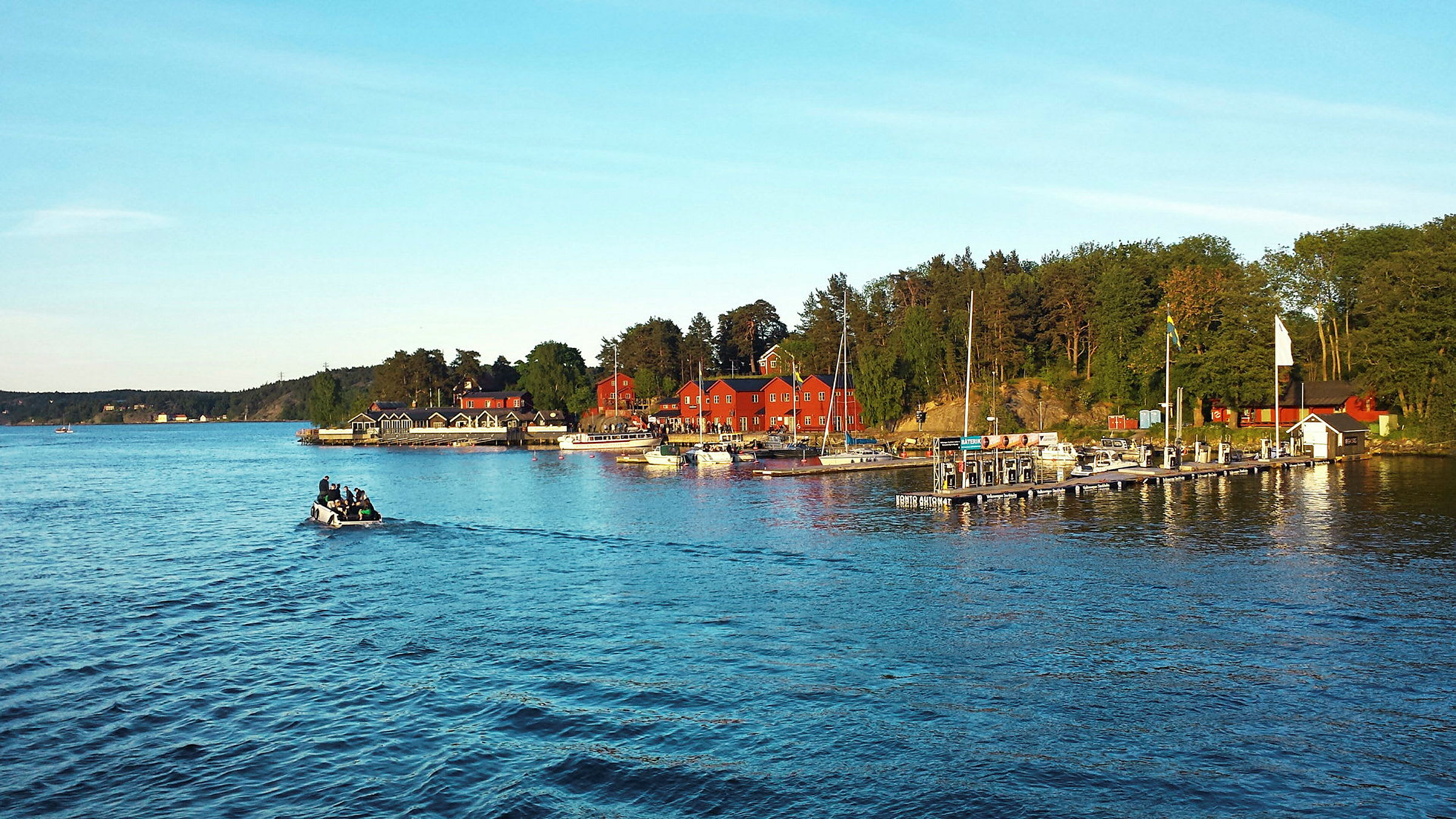 En udsigt over en lystbådehavn med røde bygninger, broer og både ved vandet. (AI-genereret tekst)