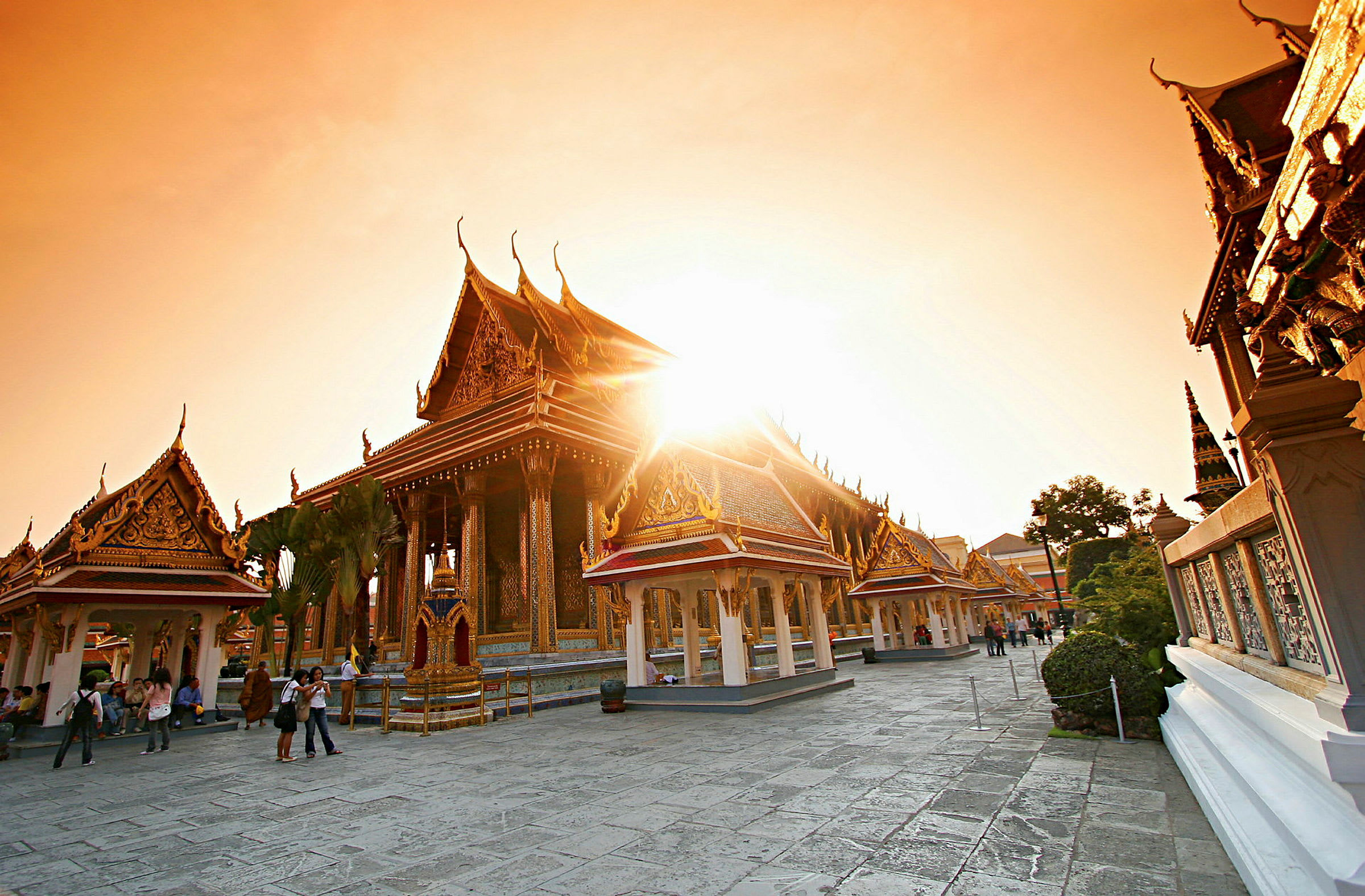 Billedet viser et thailandsk tempel med dekorerede tage og bygninger i solnedgangens lys. (AI-genereret tekst)
