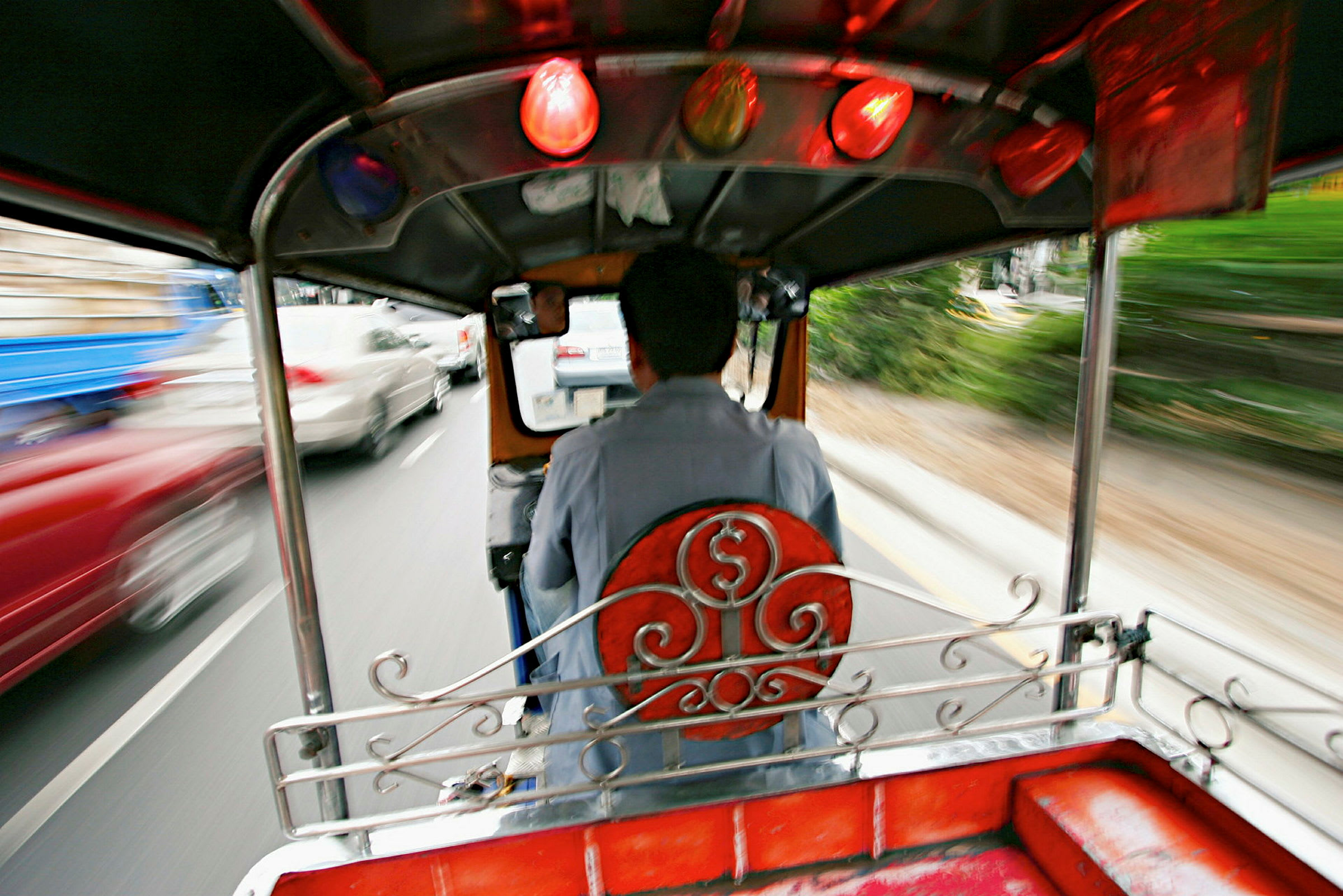 En chauffør kører en tuk-tuk på en trafikeret vej. (AI-genereret tekst)