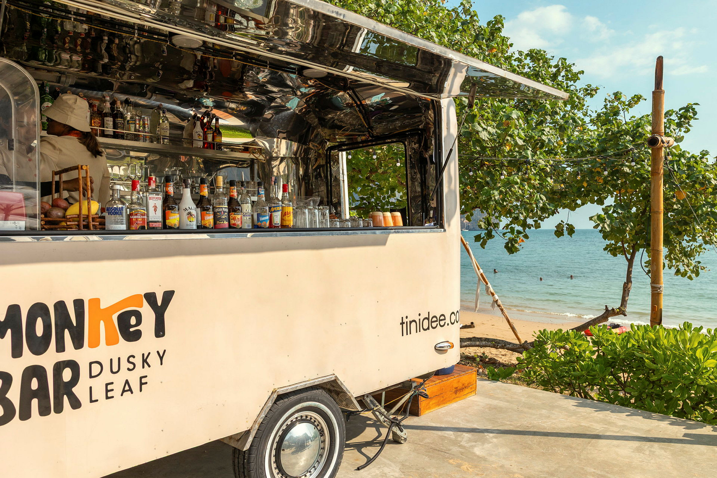 Mobil bar opstillet ved stranden, omgivet af grønt og hav i baggrunden. (AI-genereret tekst)