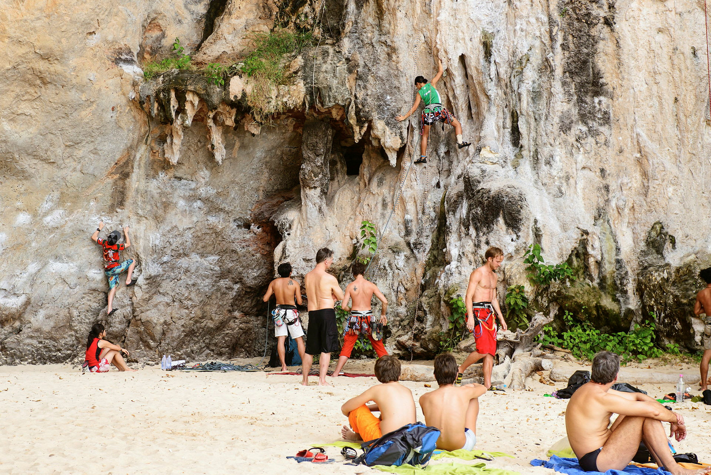 Personer klatrer på klipper ved en strand. (AI-genereret tekst)