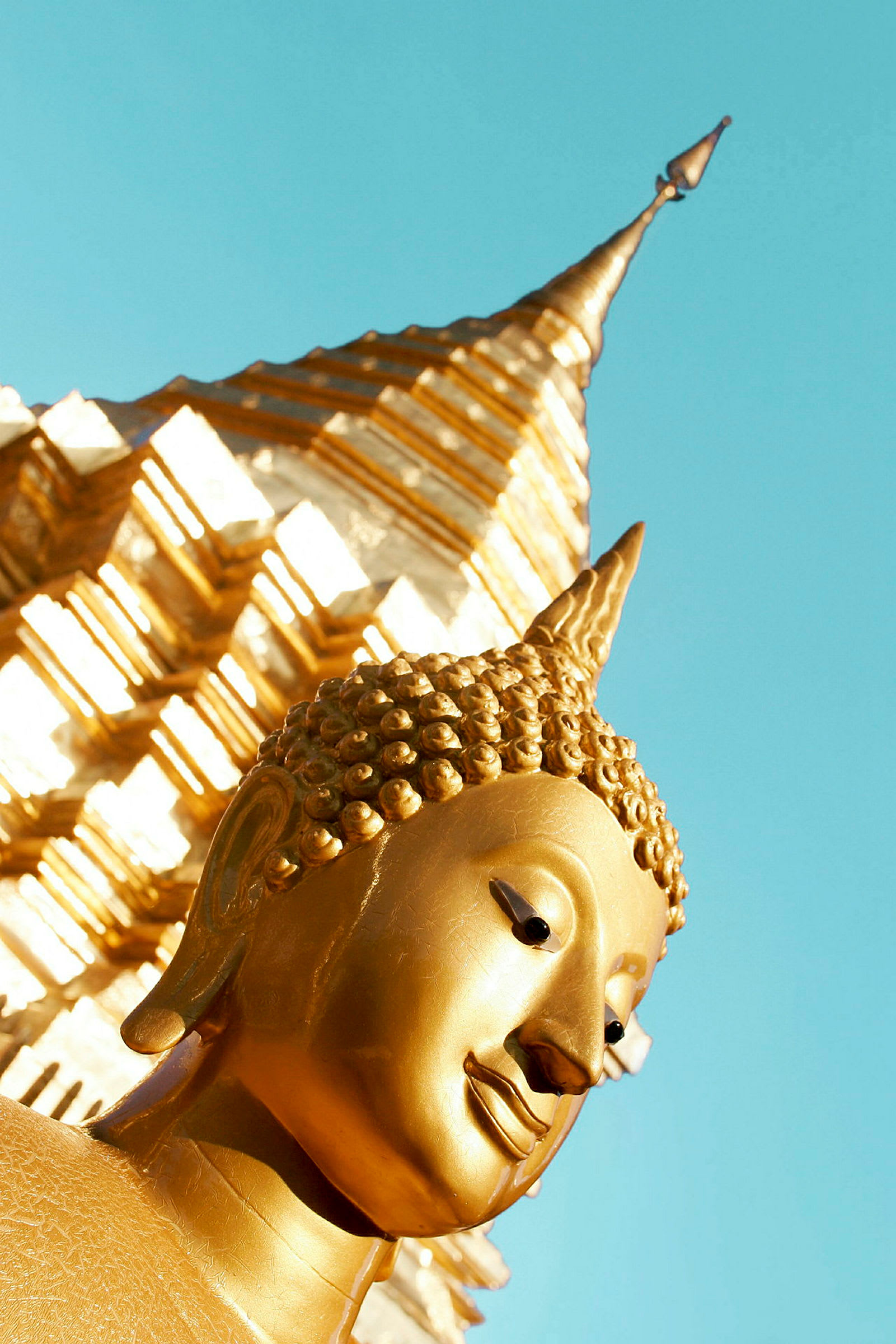 Gyldne detaljer af en buddhistisk statue med en stupa i baggrunden. (AI-genereret tekst)