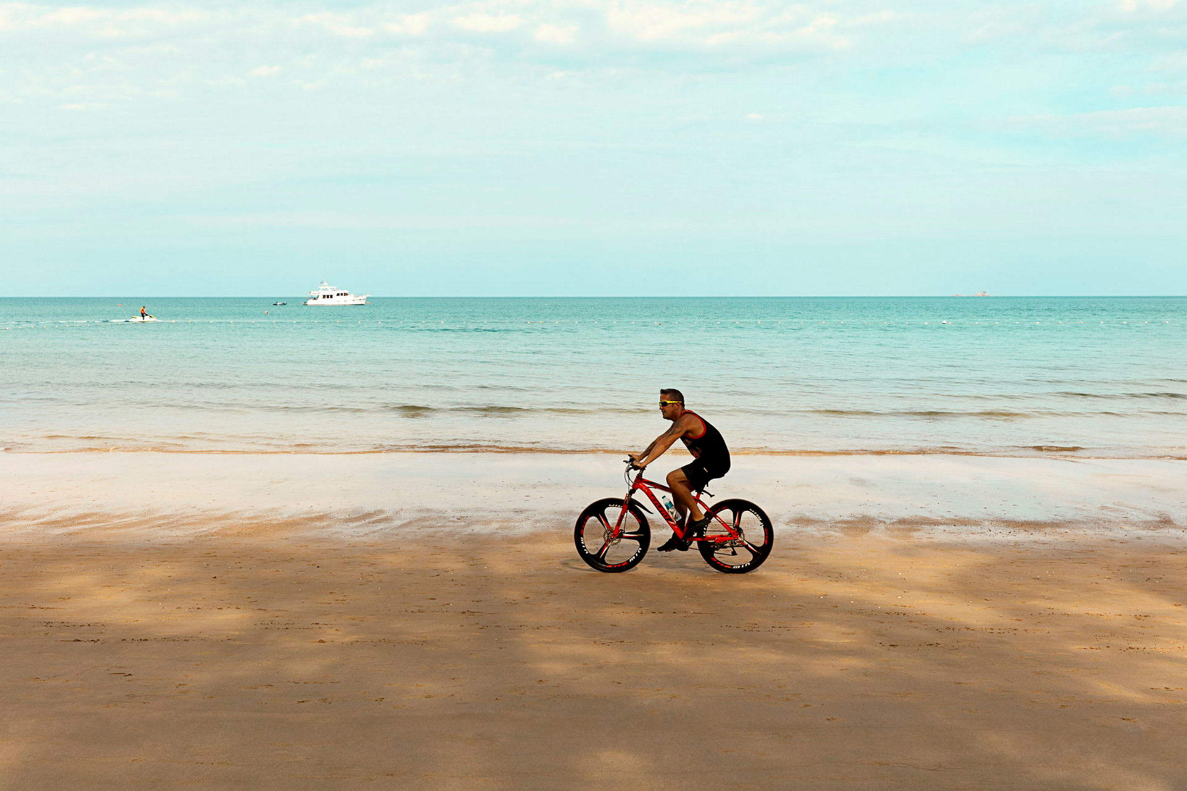 En person cykler ved en sandstrand med havet i baggrunden. (AI-genereret tekst)
