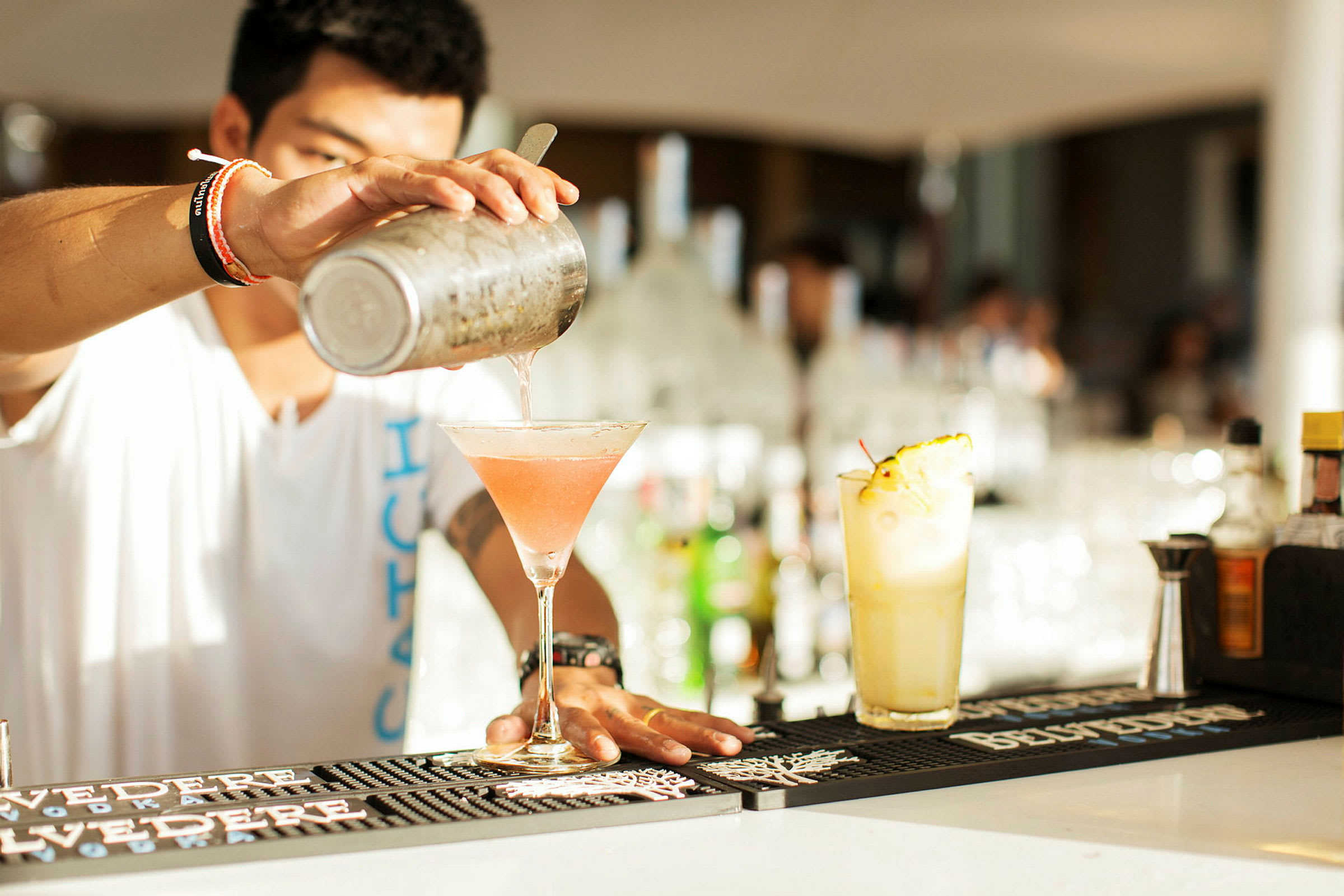 En cocktail blandes og hældes op i et glas på en bardisk. (AI-genereret tekst)