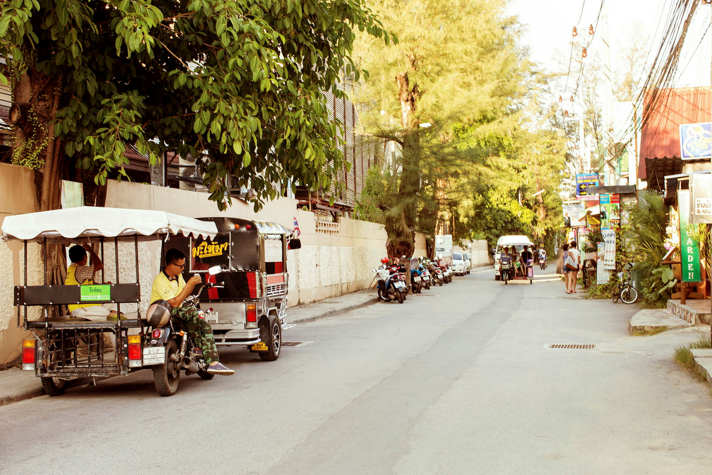 En gade med tuk-tuk-køretøjer og motorcykler parkeret langs siden. (AI-genereret tekst)