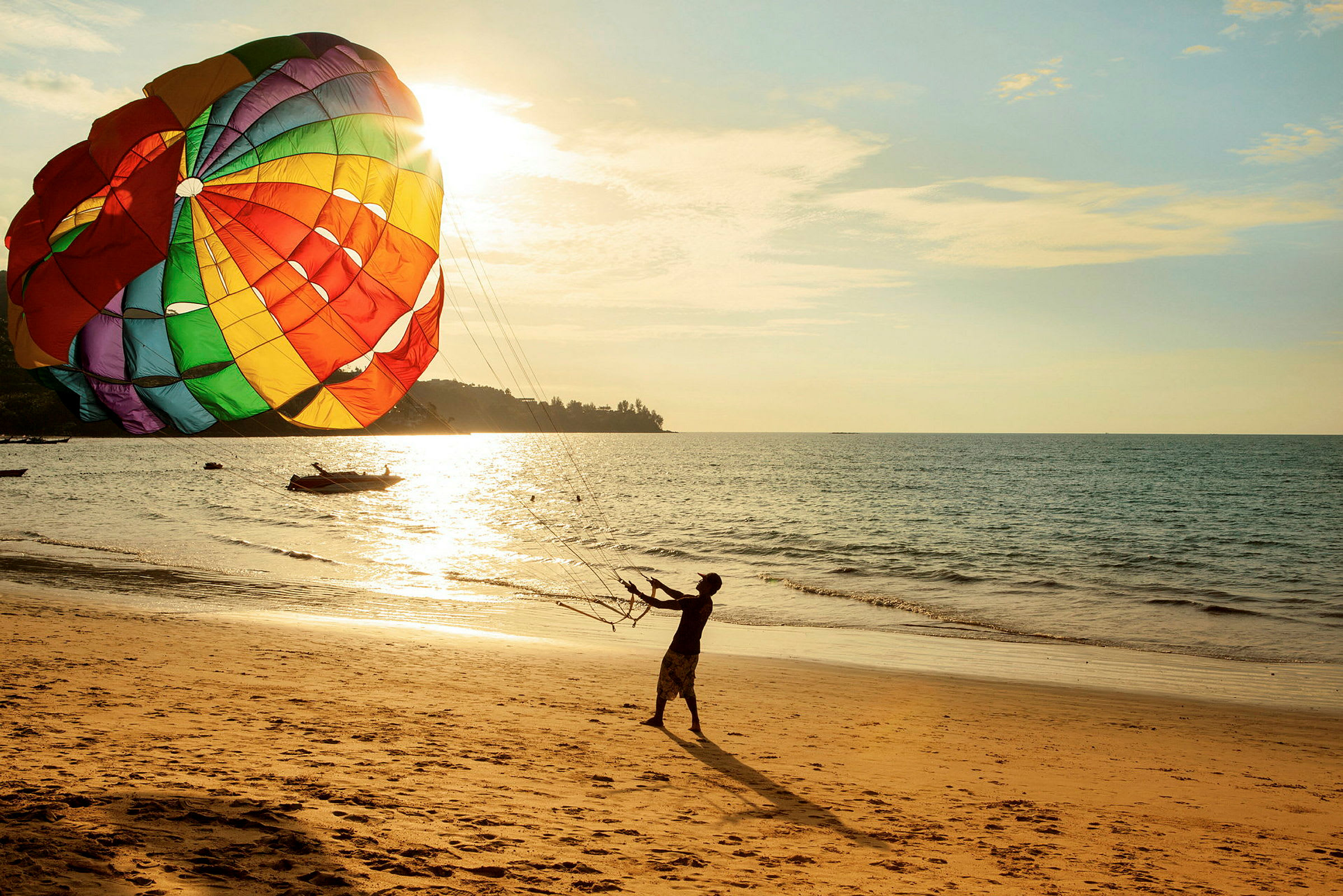 Person holder linjer til en stor farverig parasail på en solbeskinnet strand. (AI-genereret tekst)
