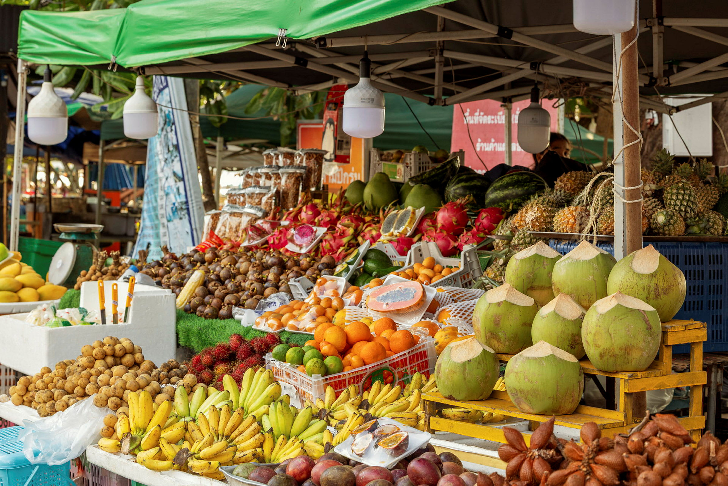 Markedsbod med et stort udvalg af tropiske frugter inklusive bananer, kokosnødder og mangostan. (AI-genereret tekst)