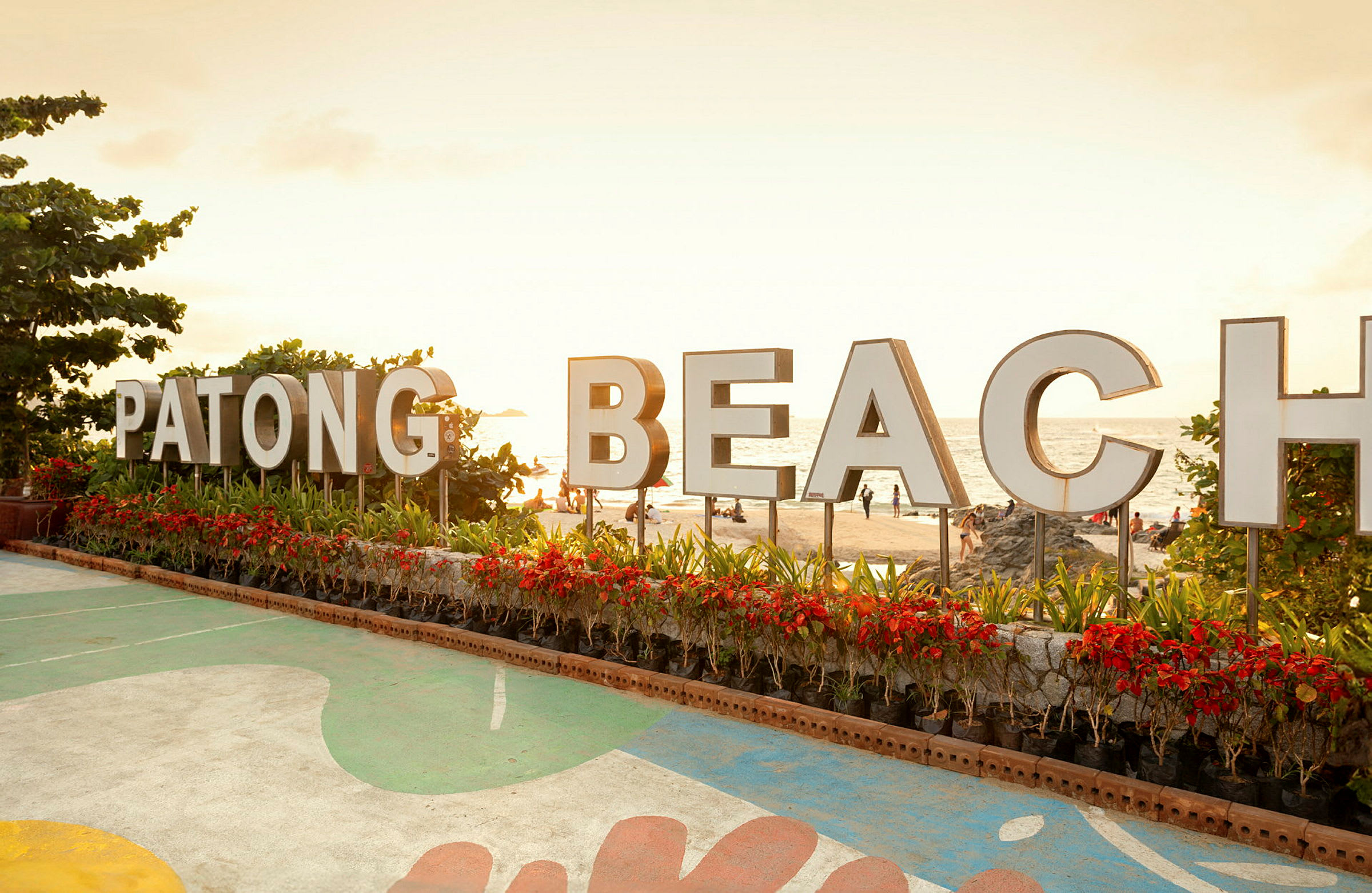 Skilt med teksten 'Patong Beach' foran stranden. (AI-genereret tekst)