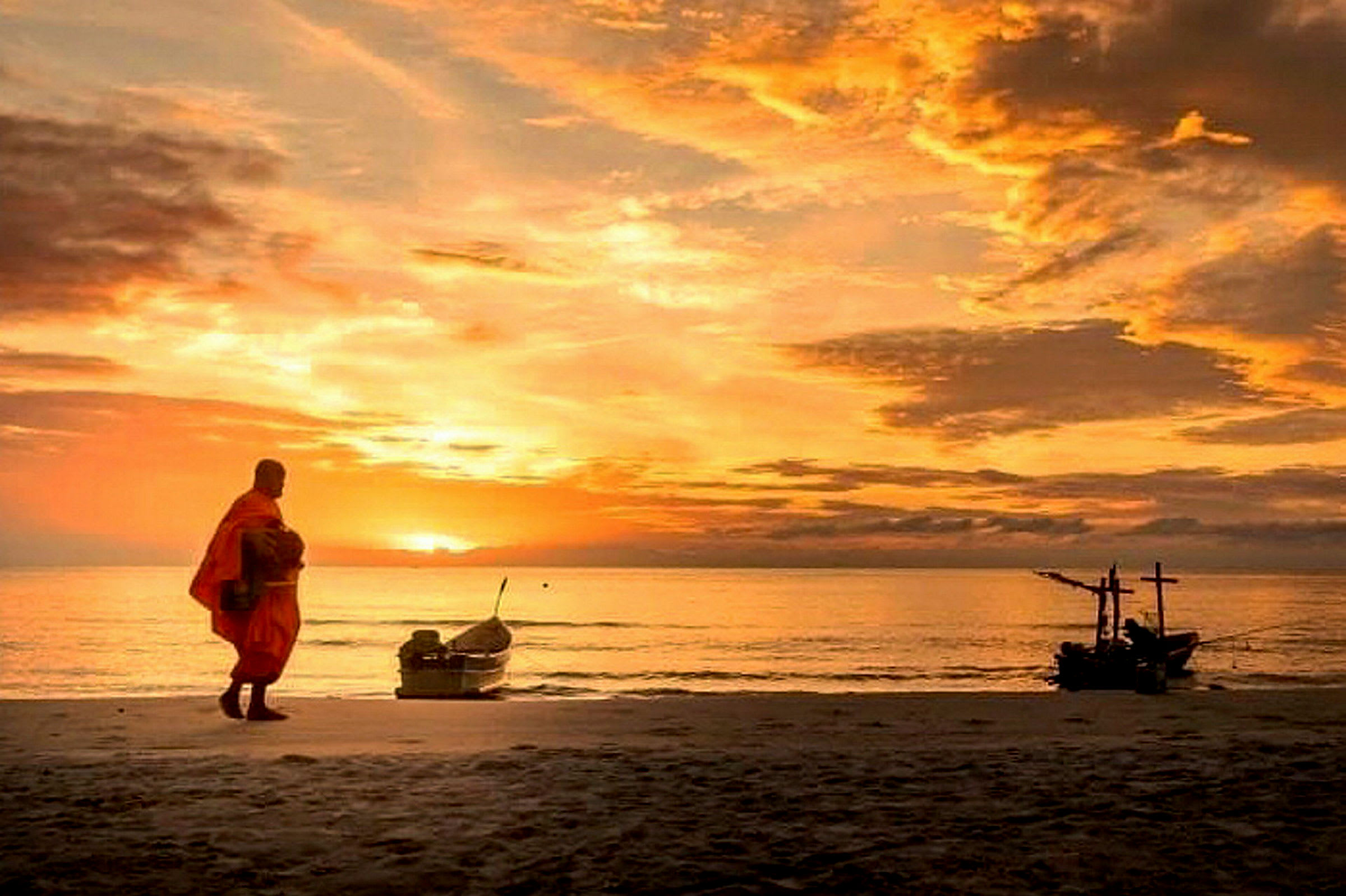 Billede af en person i orange tøj, der går på en strand ved solnedgang. En båd er synlig på vandet. (AI-genereret tekst)