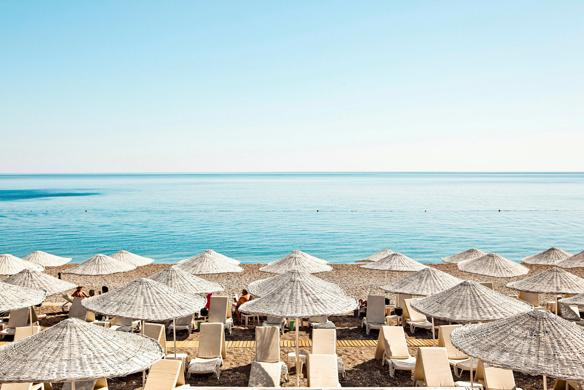 Solstole og parasoller på en strand med havet i baggrunden. (AI-genereret tekst)