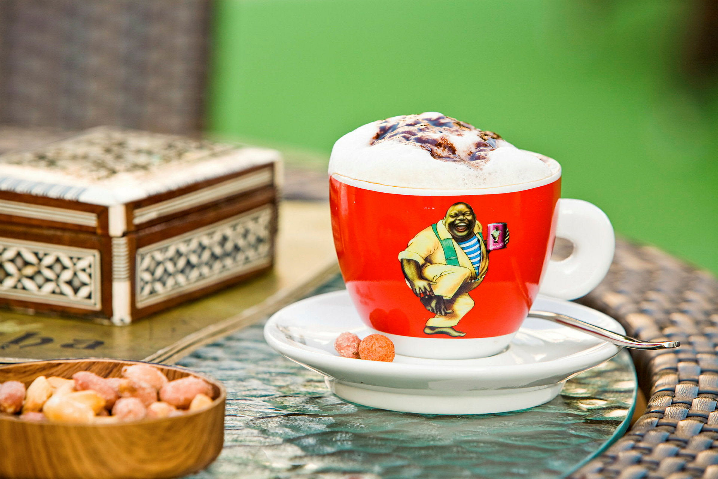 En kop kaffe med skummet mælk på et bord sammen med nogle snacks. (AI-genereret tekst)