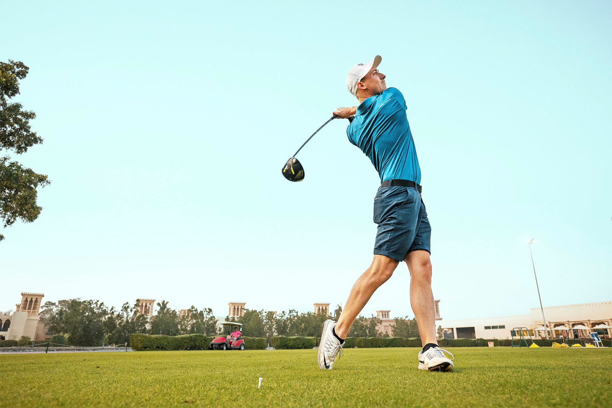 Person spiller golf og svinger en kølle på en grøn golfbane. (AI-genereret tekst)