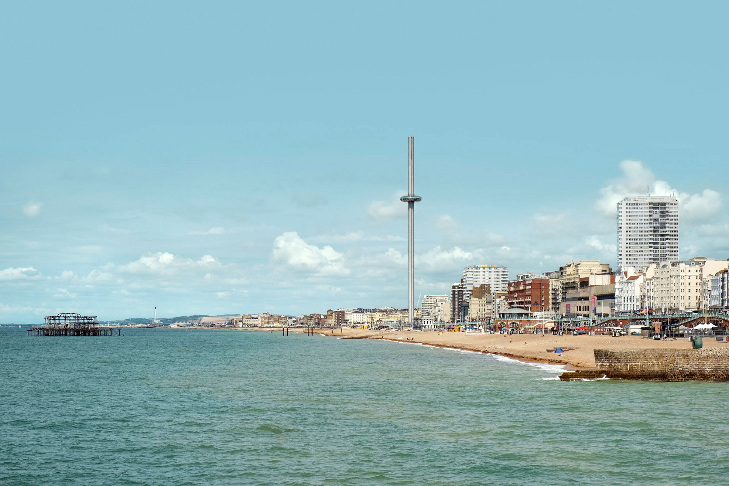 Udsigt over havet og stranden ved Brighton med i360-tårnet og bygninger i baggrunden. (AI-genereret tekst)