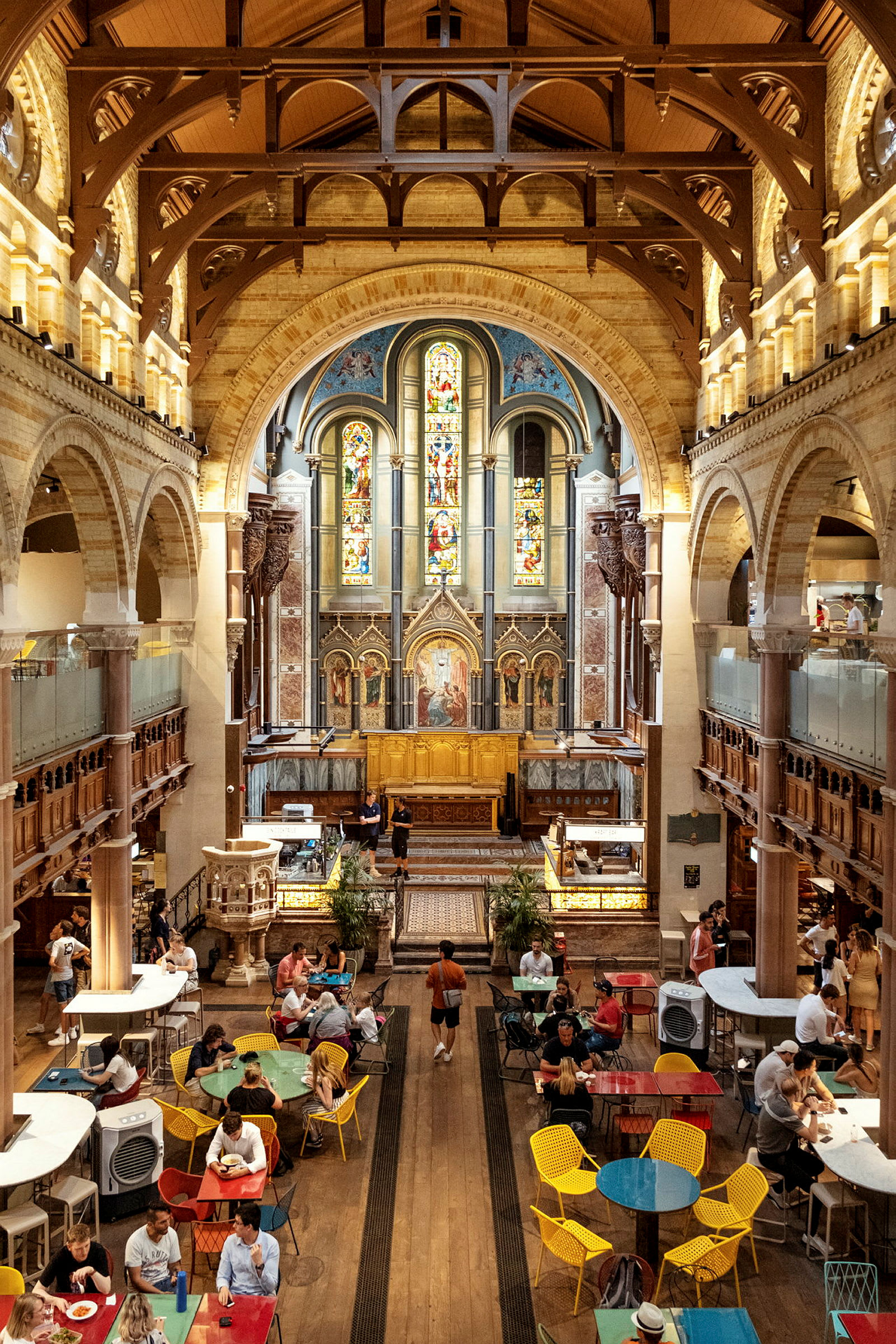 Et interiør af en kirke med farvede glasvinduer og et caféområde. (AI-genereret tekst)