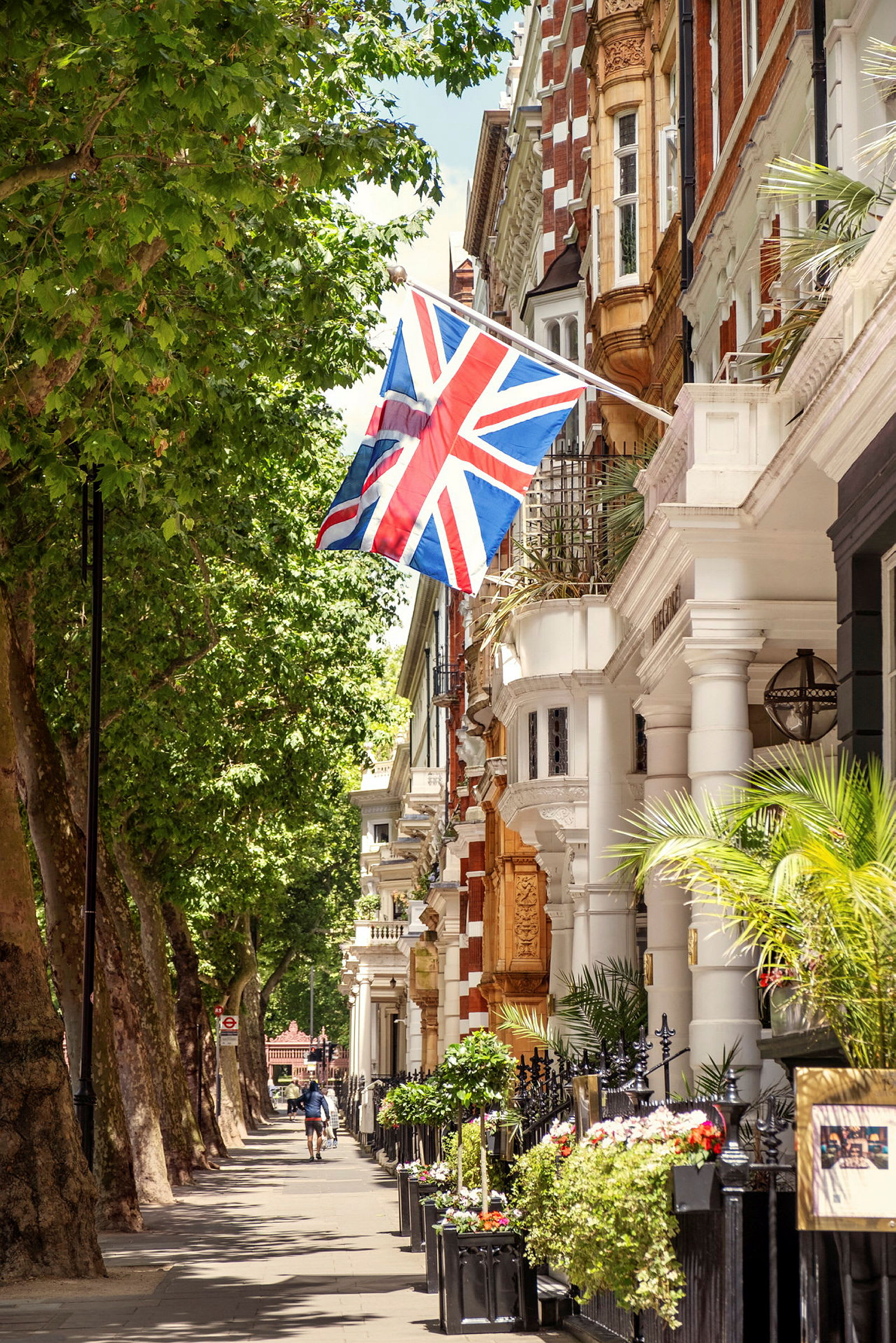 Britisk flag, der hænger fra en bygning ved en grønnende gade. (AI-genereret tekst)