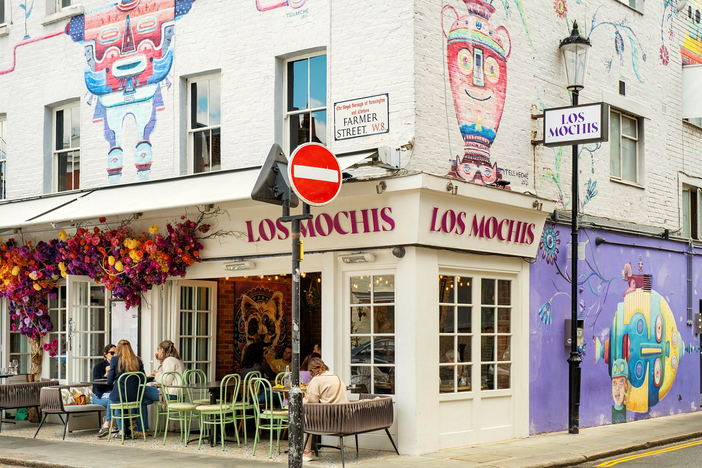 Restaurant med navnet Los Mochis, dekoreret med farverige vægmalerier og blomster. (AI-genereret tekst)