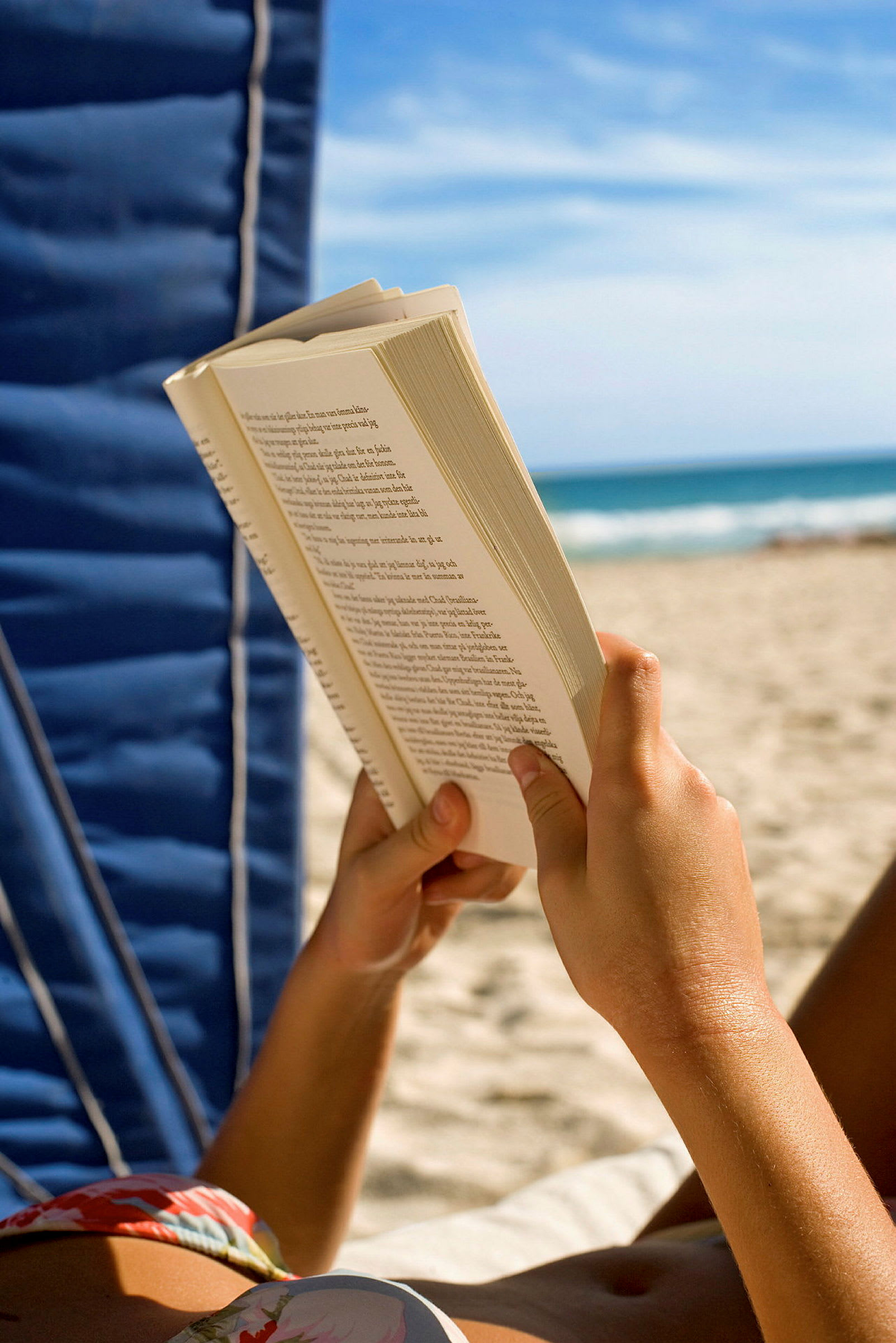 En person læser en bog på en strand. (AI-genereret tekst)