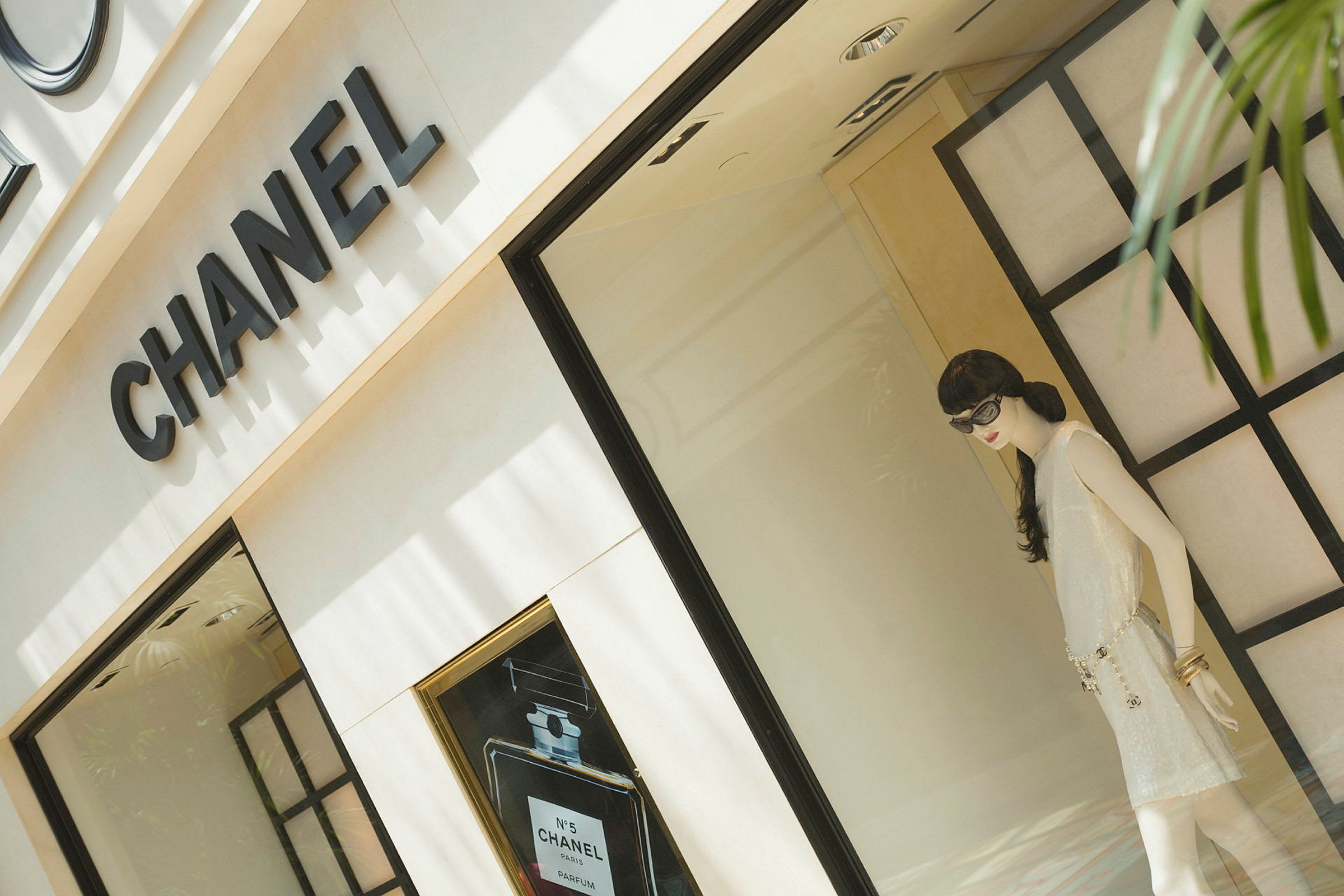 Et udstillingsvindue tilhørende en Chanel-butik, indeholdende en mannequin iført en elegant beklædning. (AI-genereret tekst)