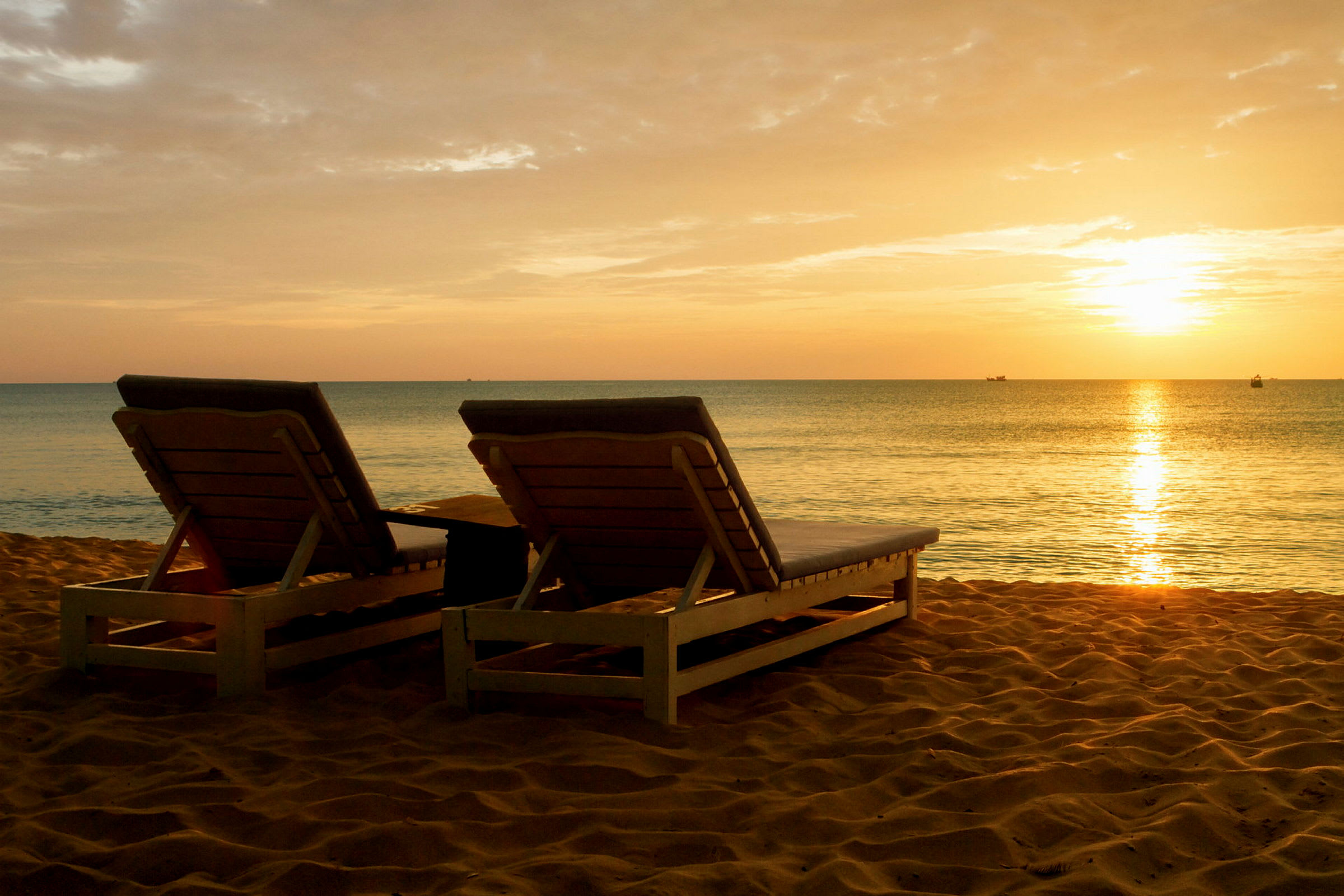 To liggestole på en sandstrand ved solnedgang. (AI-genereret tekst)