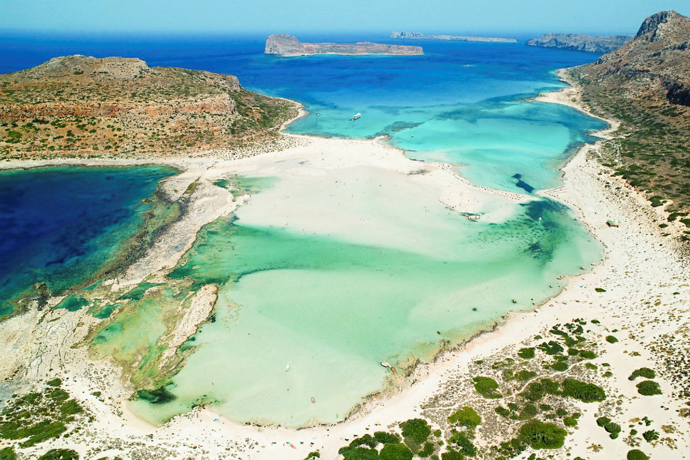 Luftfoto af en strand med turkis vand og omkringliggende klitter. (AI-genereret tekst)