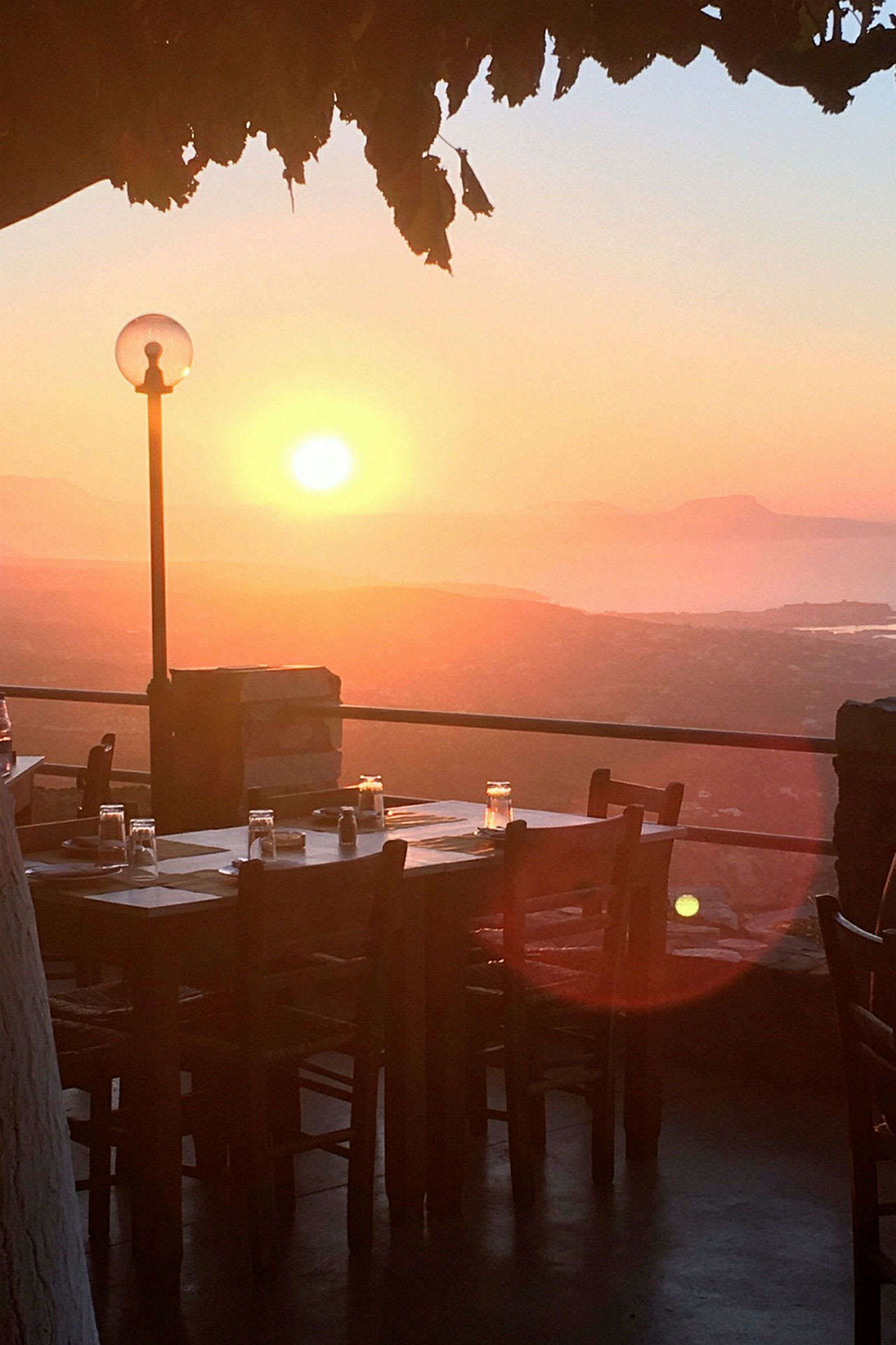 Et bord dækket til middag udendørs ved solnedgang med udsigt over landskabet. (AI-genereret tekst)