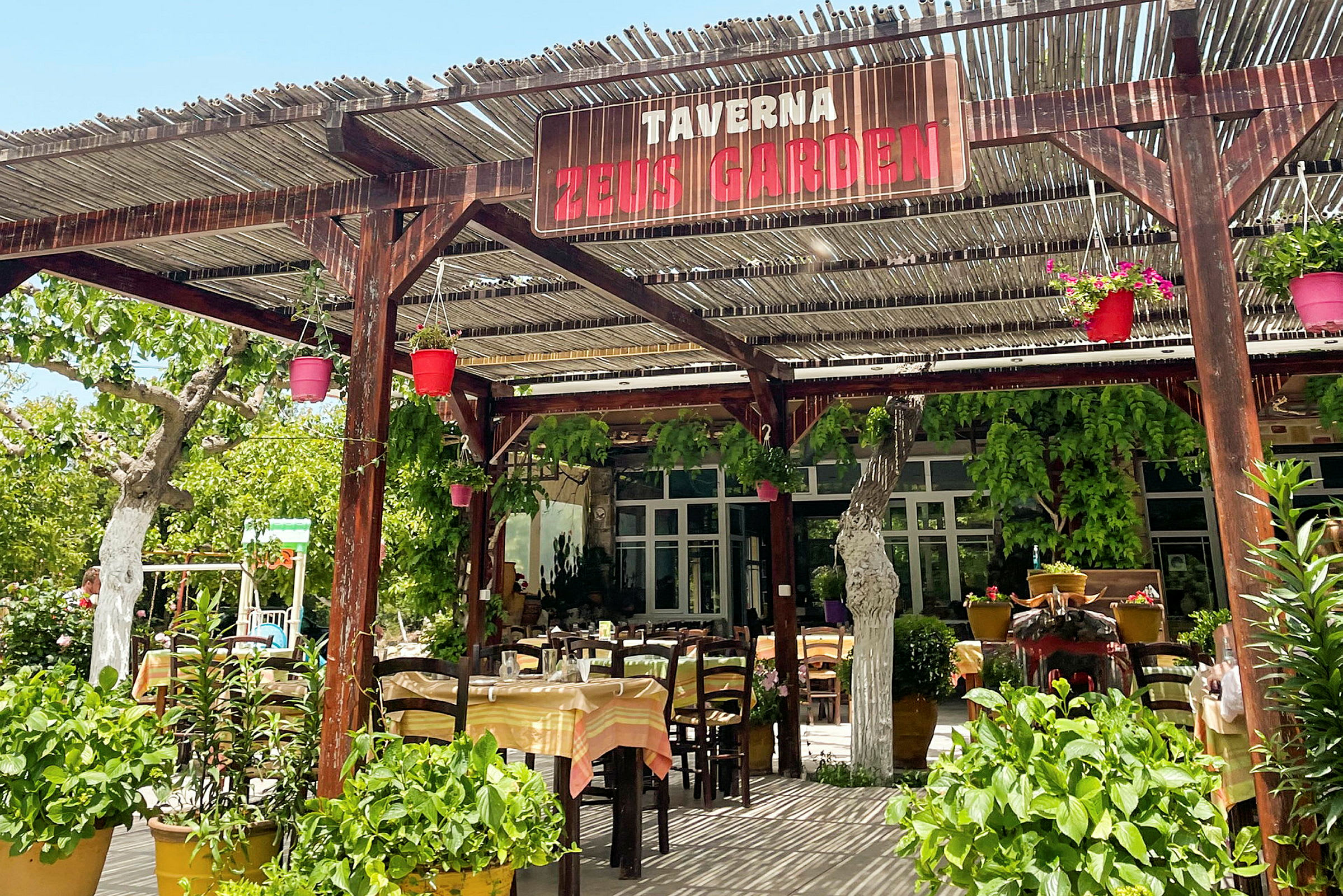 En taverna med udendørsservering og grønne planter. (AI-genereret tekst)