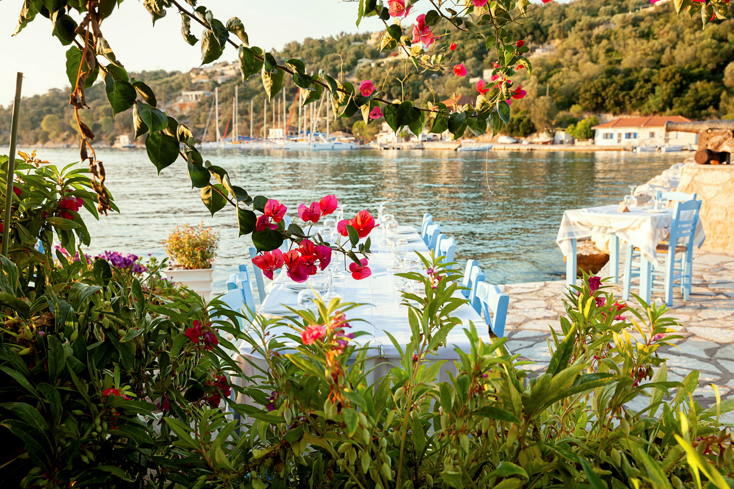 Strandrestaurant med udsigt over havet og omgivet af blomster. (AI-genereret tekst)