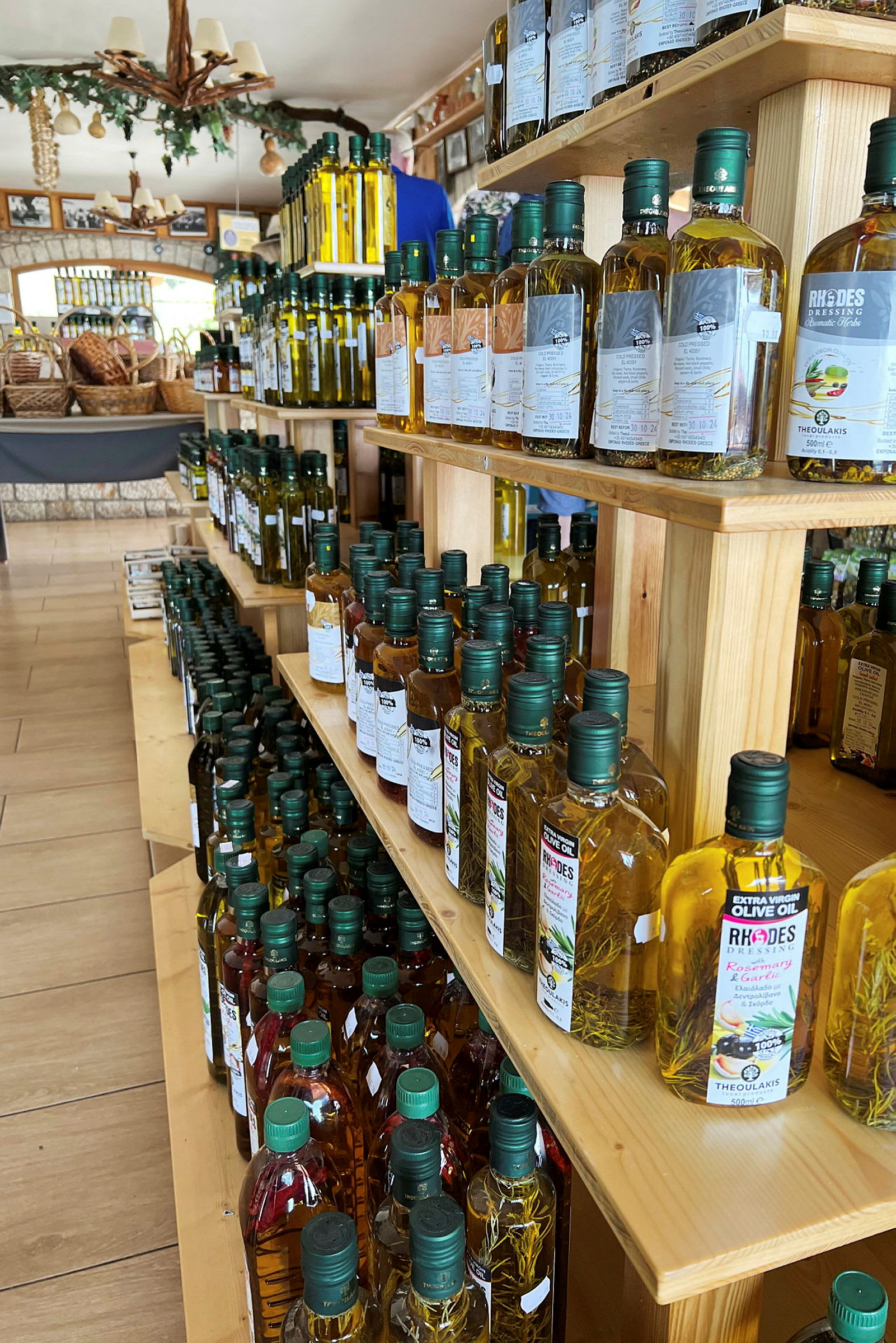 Hylde i en butik fyldt med flasker olivenolie og andre produkter. (AI-genereret tekst)