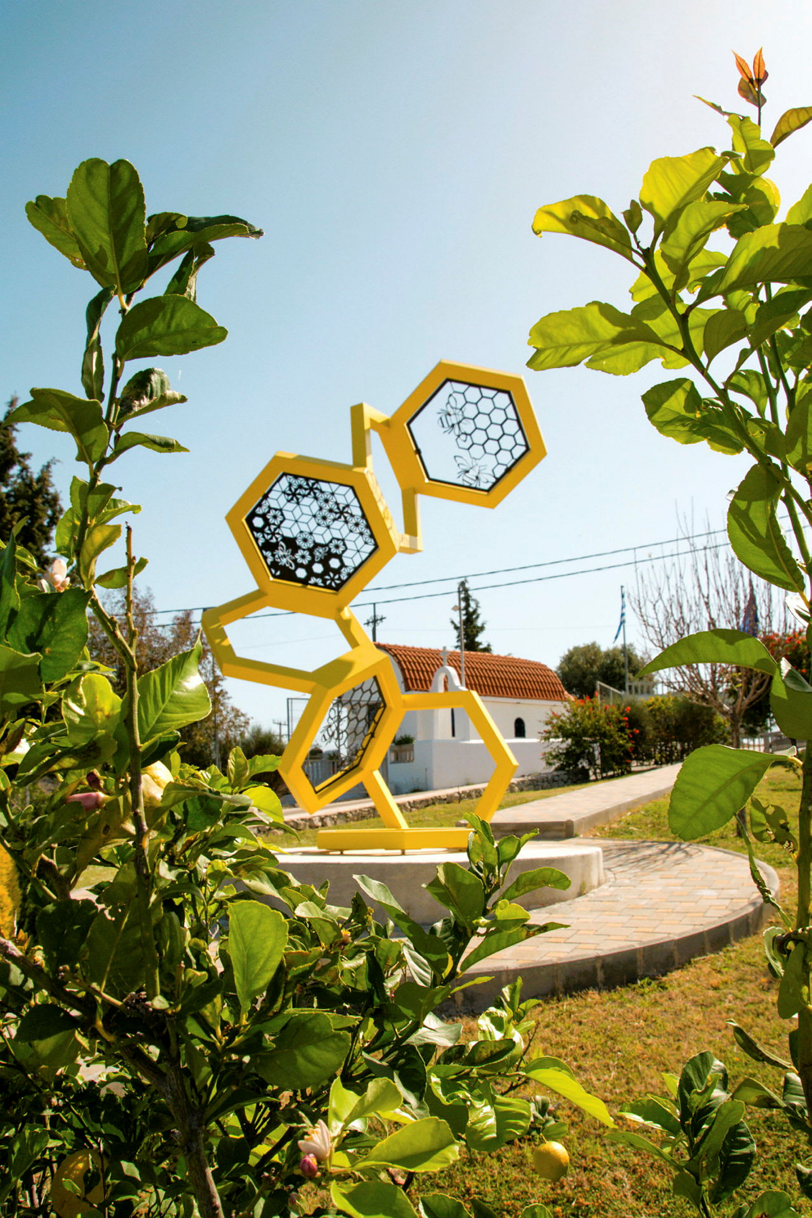 En skulptur af gule sekskanter står i en have omgivet af grønt. (AI-genereret tekst)