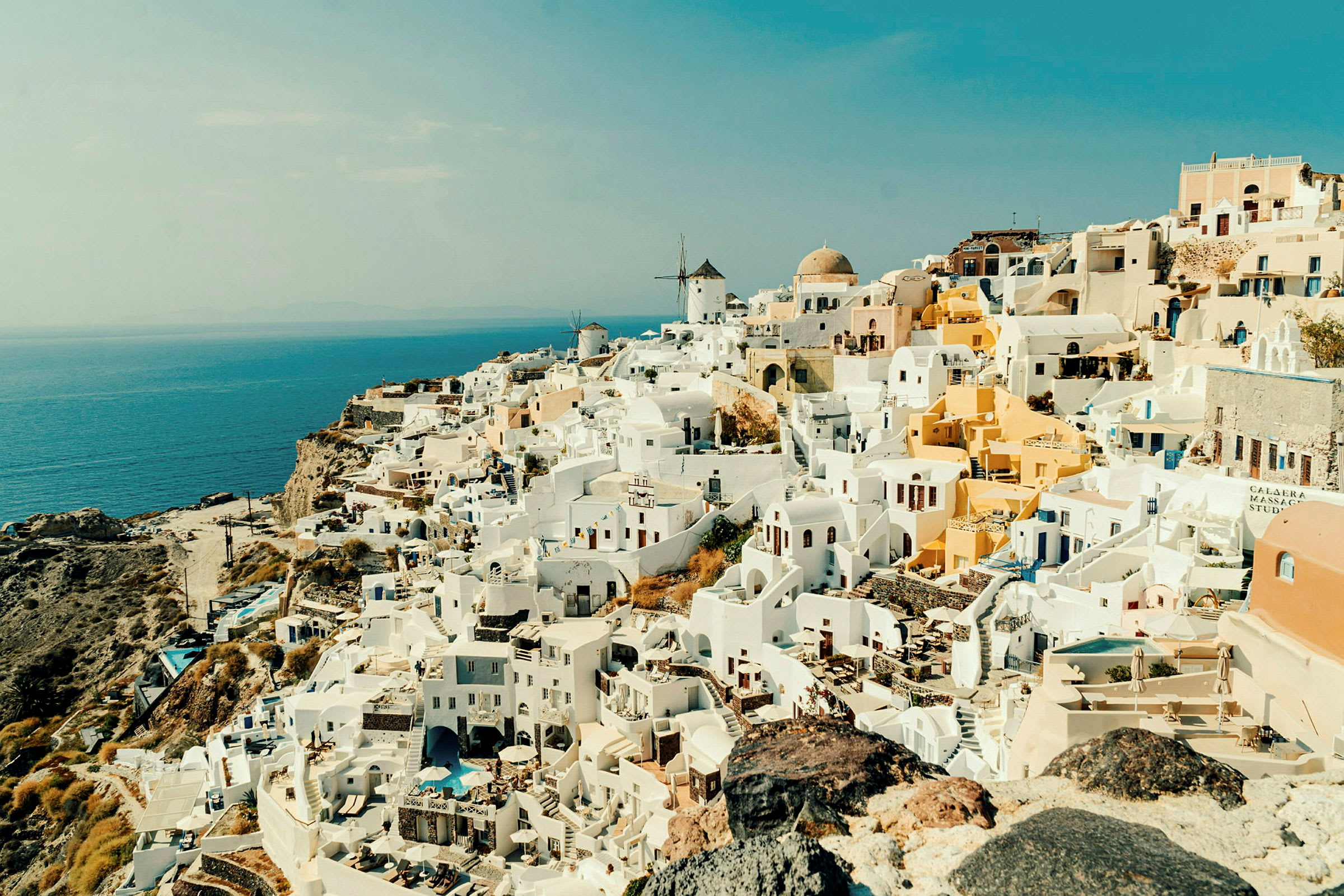 Udsigt over en by med hvidmalede huse på en klippe ved havet. (AI-genereret tekst)
