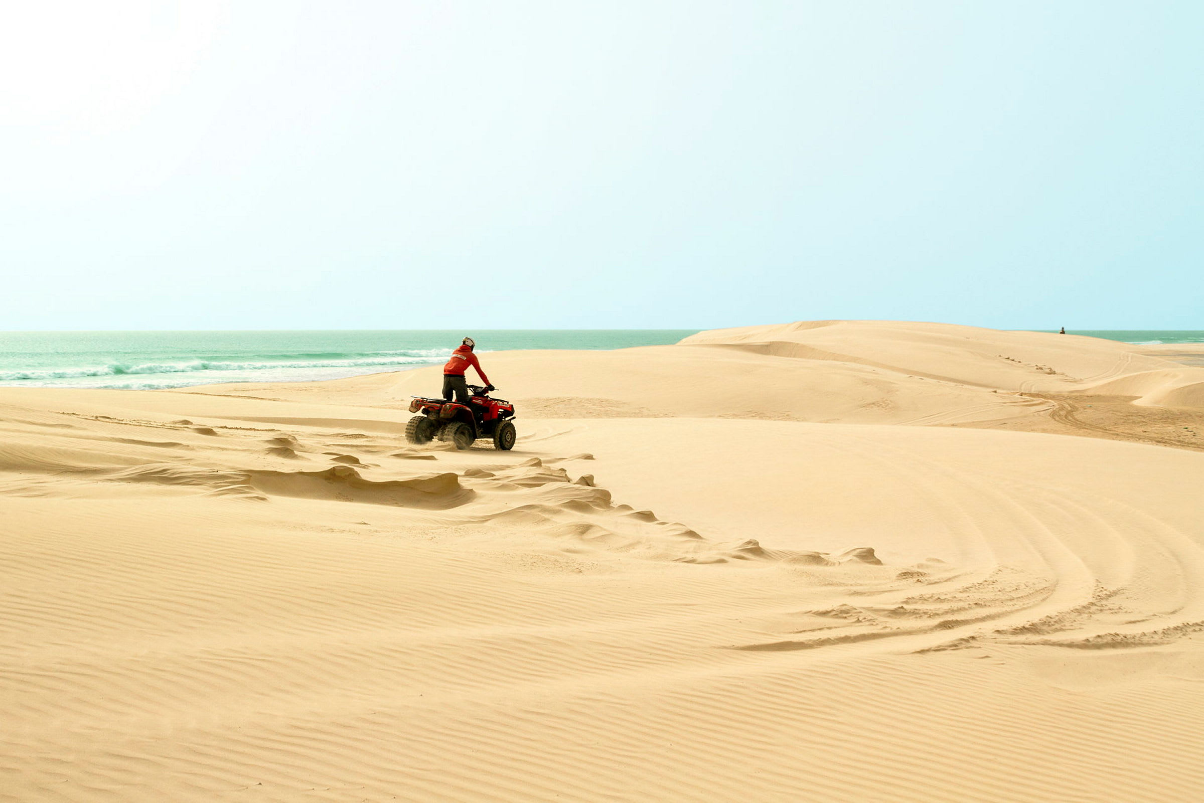 Person, der kører en ATV over sandklitter ved havet. (AI-genereret tekst)