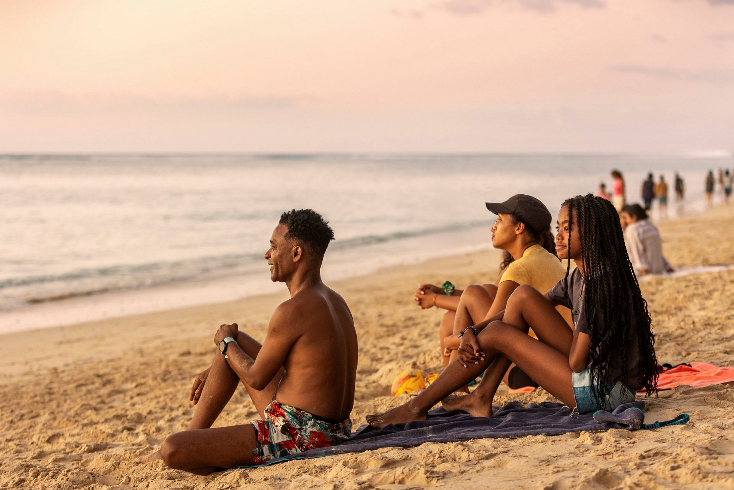 Personer sidder på en strand og kigger ud mod havet. (AI-genereret tekst)