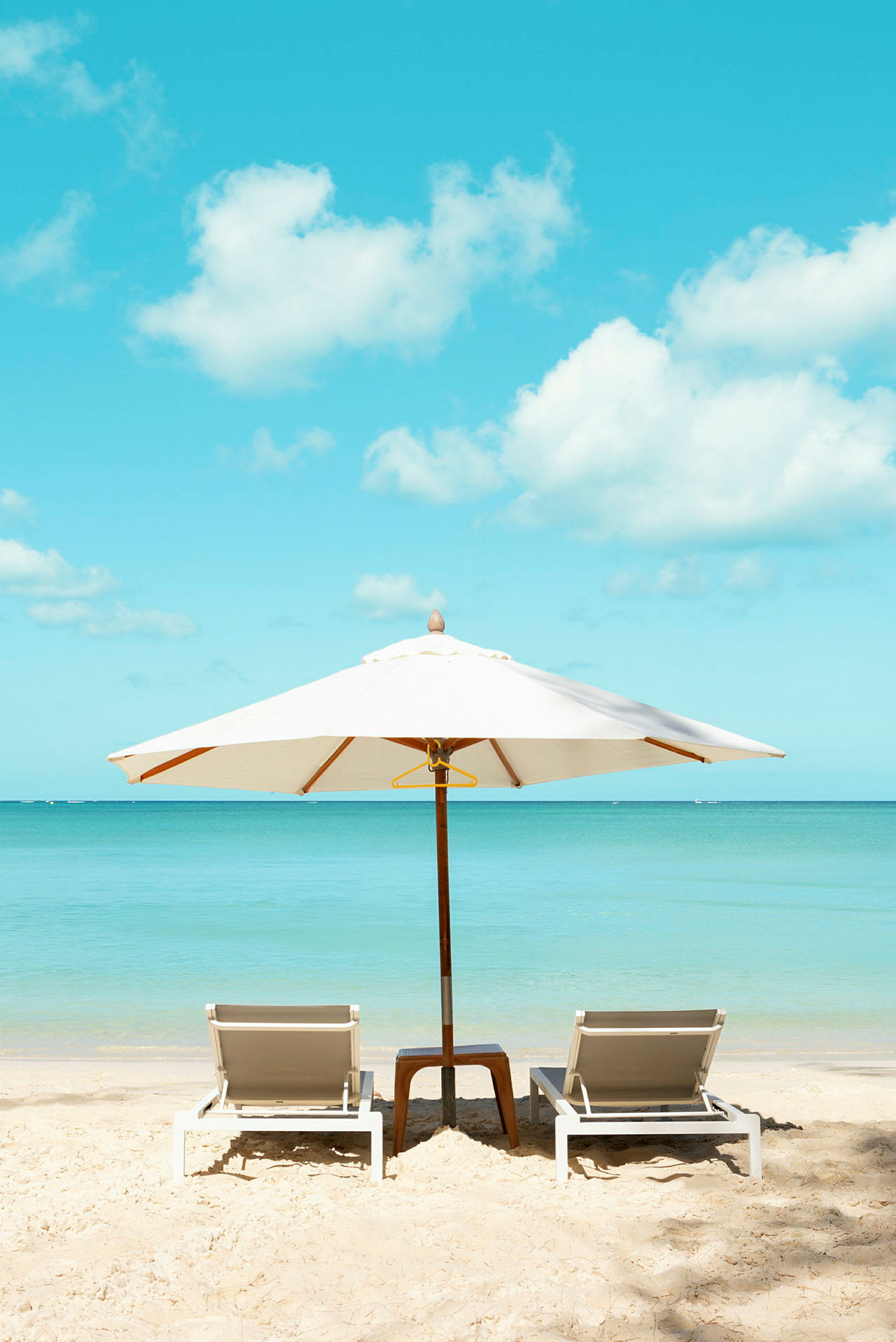 Solsenge med parasol på en strand tæt på havet. (AI-genereret tekst)