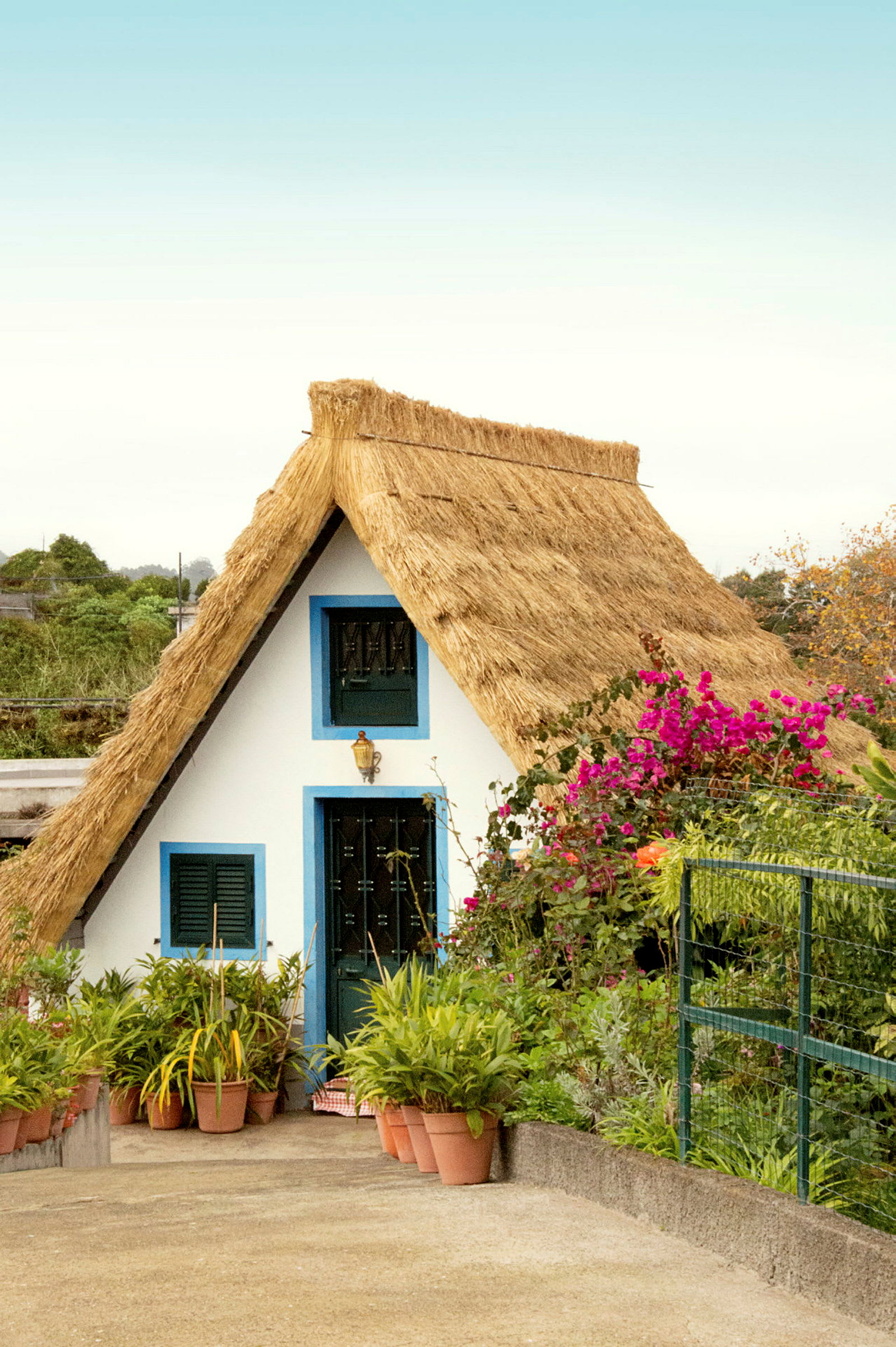 Et traditionelt hvidt hus med et stråtag og farverige blomster omkring. (AI-genereret tekst)