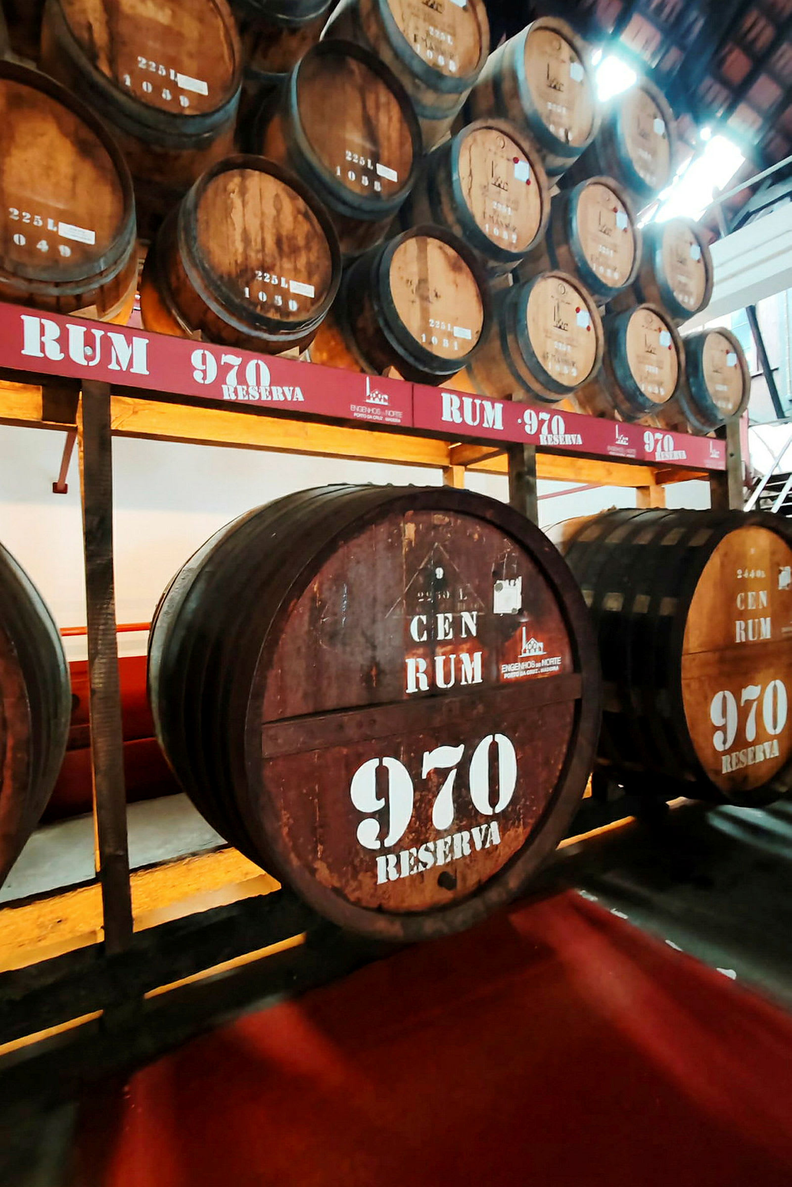 Flere store trætønder på en lagerhylde, mærket med teksten 'Rum 970 Reserva'. (AI-genereret tekst)