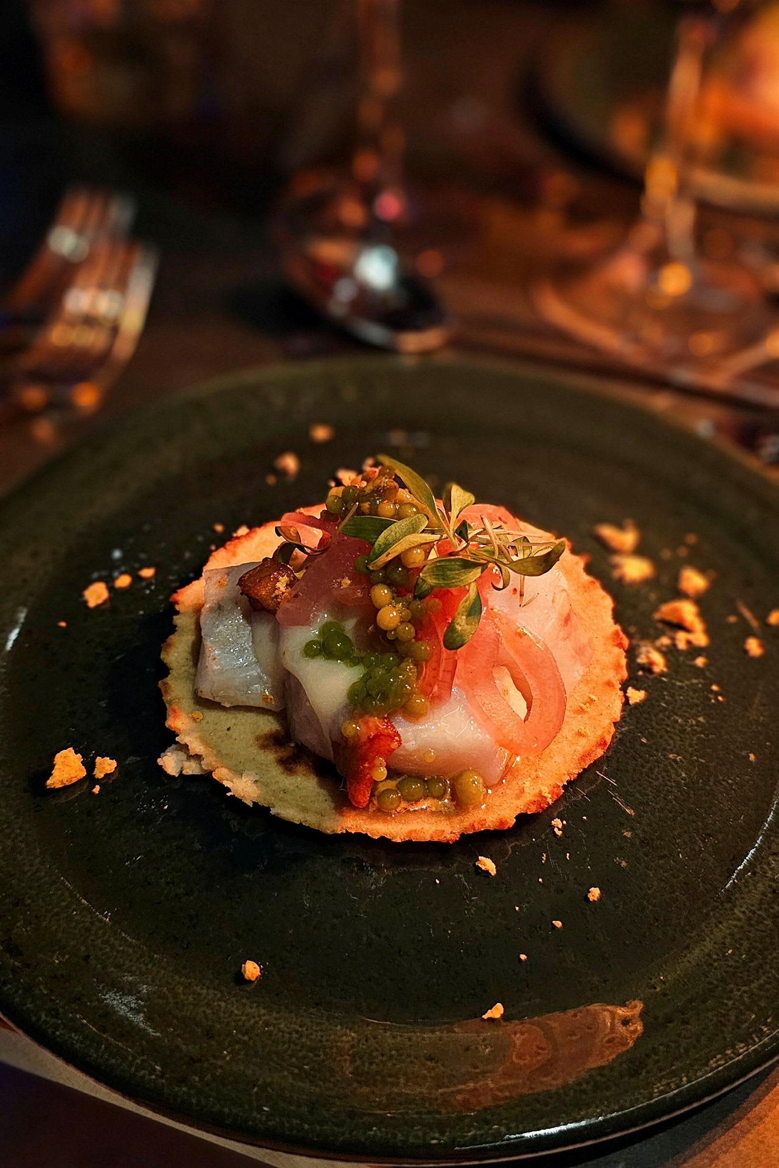 En tallerken med en gourmetforret bestående af tyndt brød med fisk, grøntsager og urter. (AI-genereret tekst)