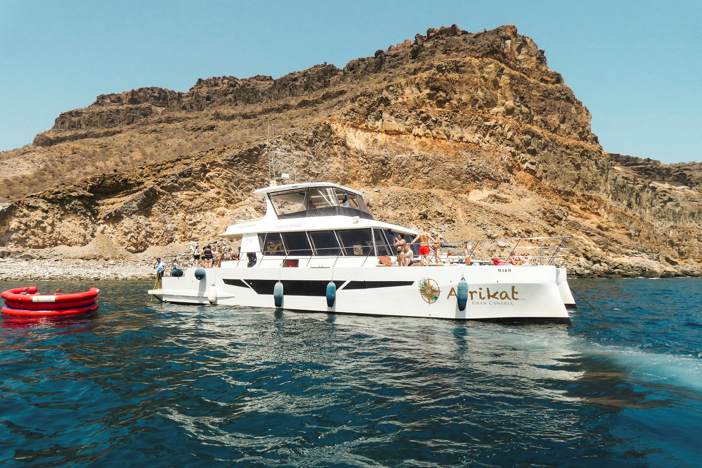 En båd ved en klippefyldt kyst med klart blåt vand. (AI-genereret tekst)