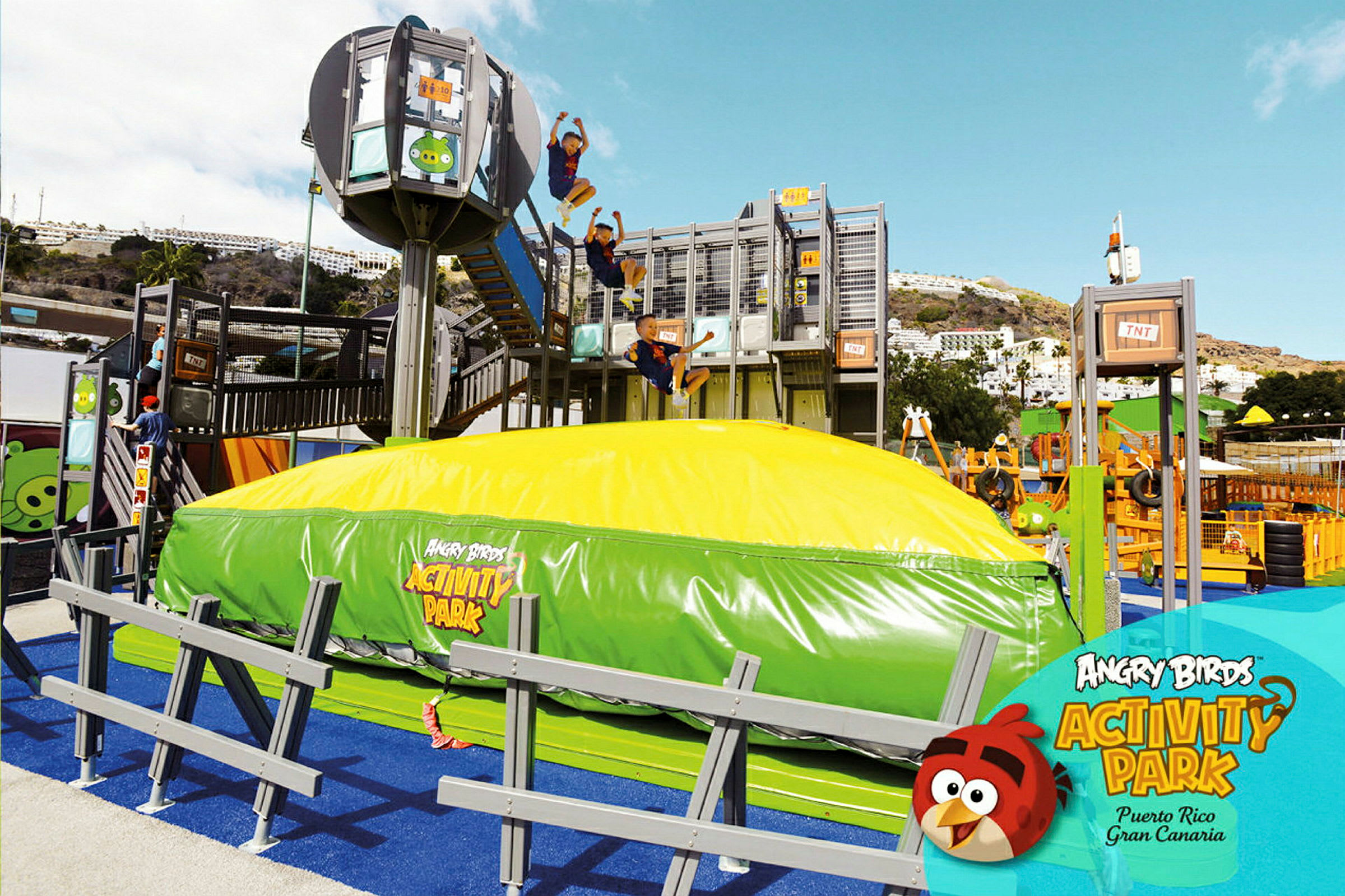 Et udendørs aktivitetsområde ved Angry Birds Activity Park med en stor oppustelig pude og flere legestrukturer. (AI-genereret tekst)