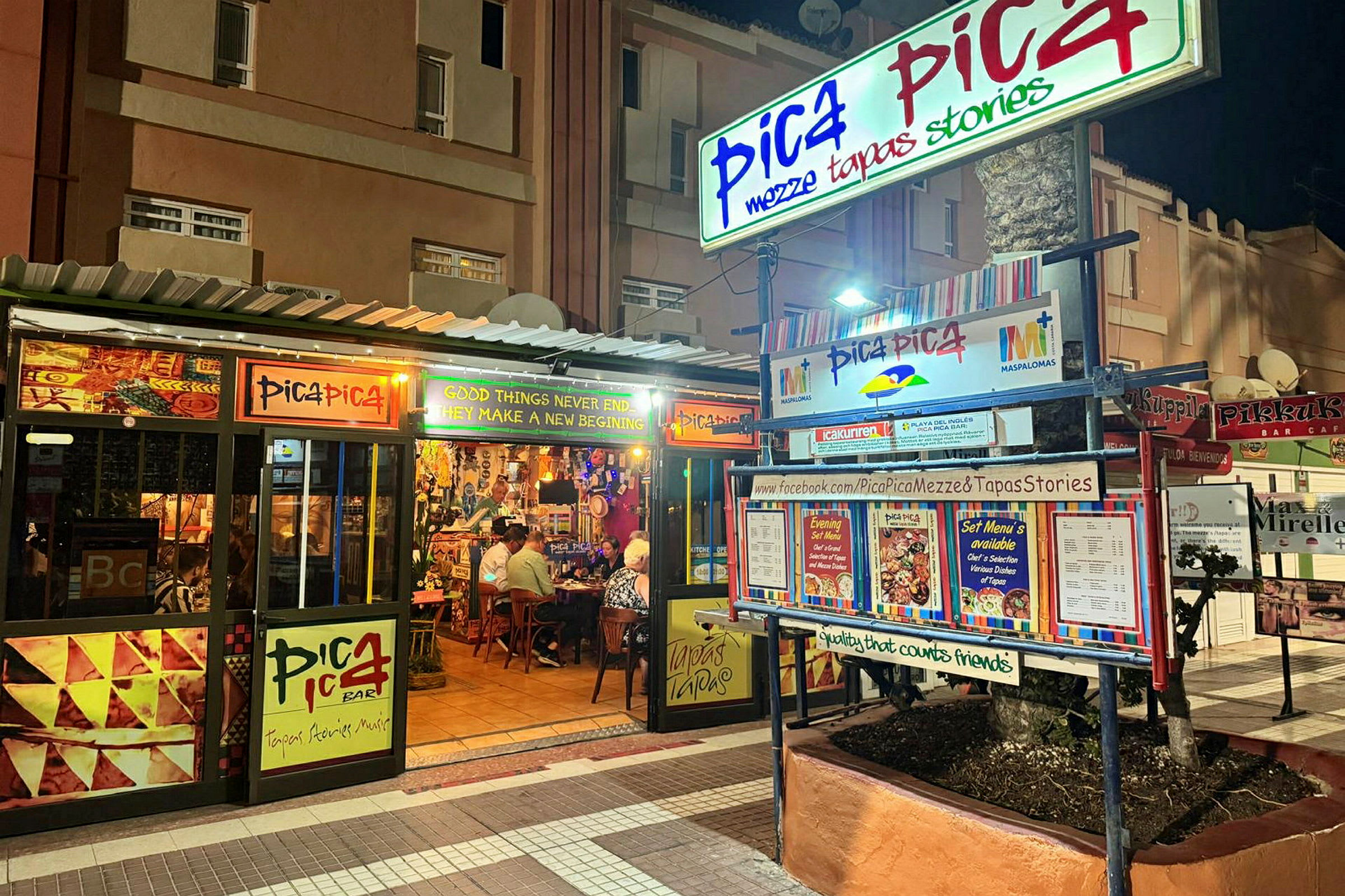 En restaurant ved navn Pica Pica ses om natten. Skilte og menuer pryder eksteriøret. (AI-genereret tekst)