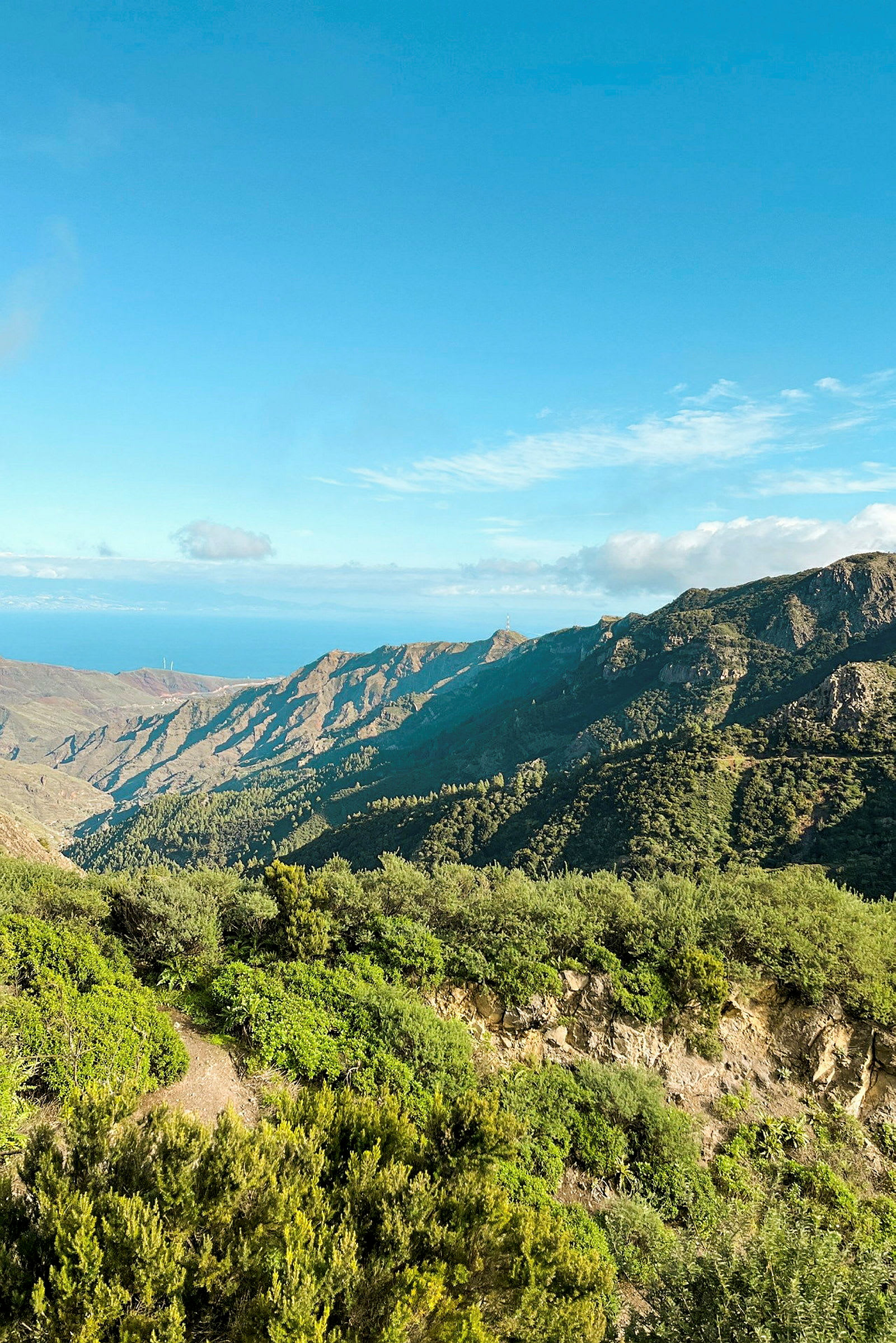 Bjerglandskab med grøn vegetation og blå himmel. (AI-genereret tekst)
